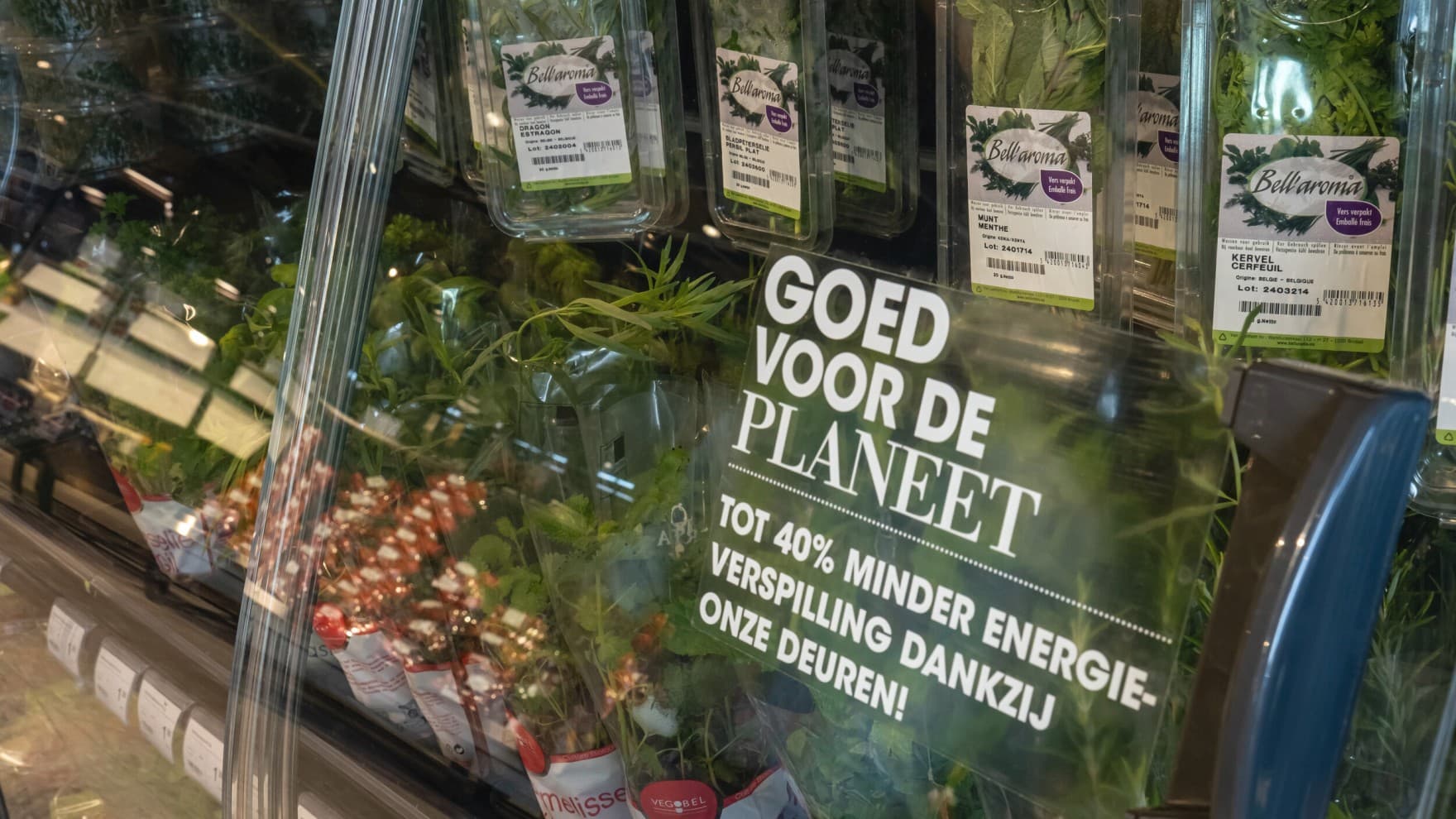 Kruidenrek in de supermarkt met op de glazen deur de tekst: "goed voor de planeet, tot 40% minder energieverspilling dankzij deze deuren!"