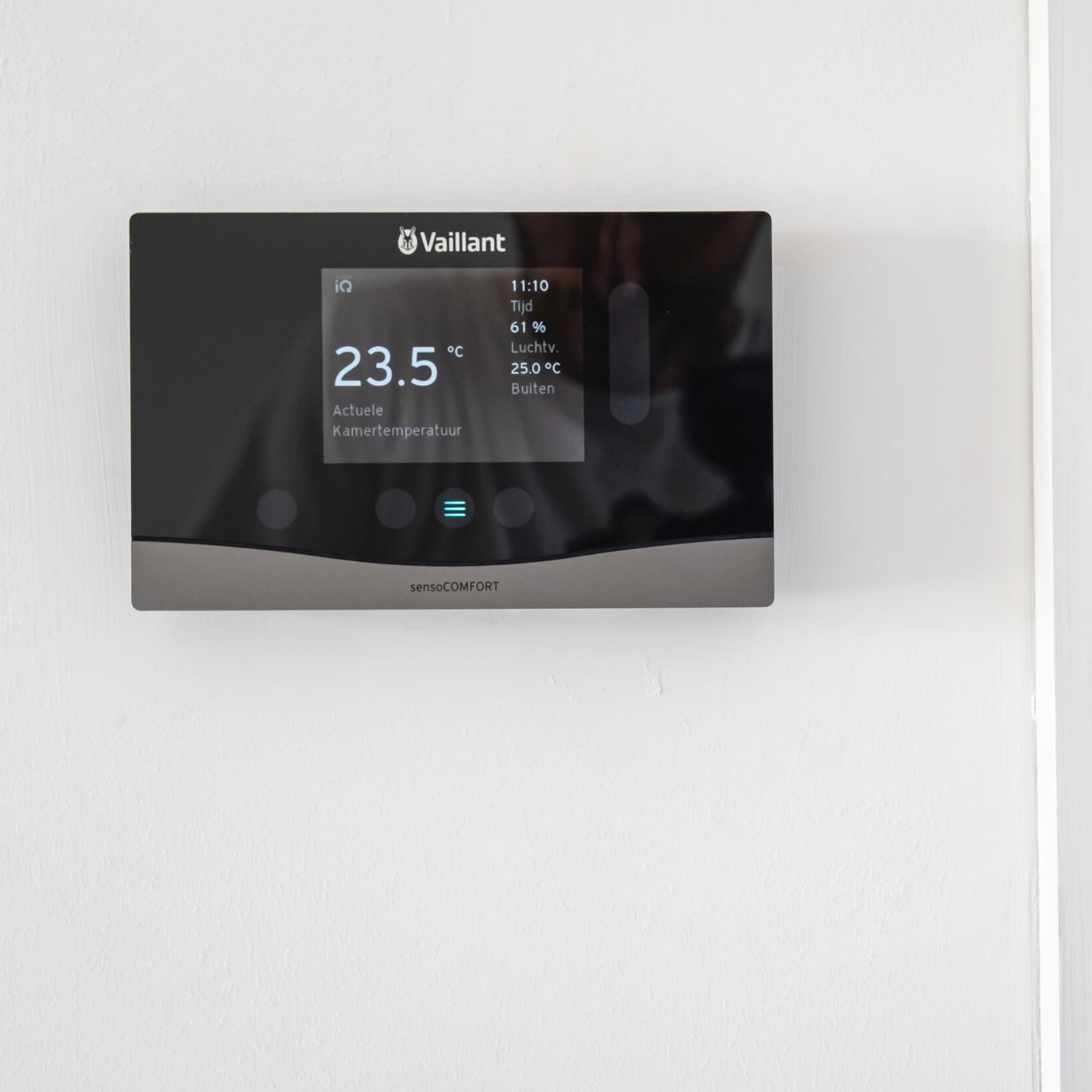 sensoCOMFORT weersafhankelijke regelaar tegen een witte muur. De gewenste temperatuur staat ingesteld op 23,5 °C.