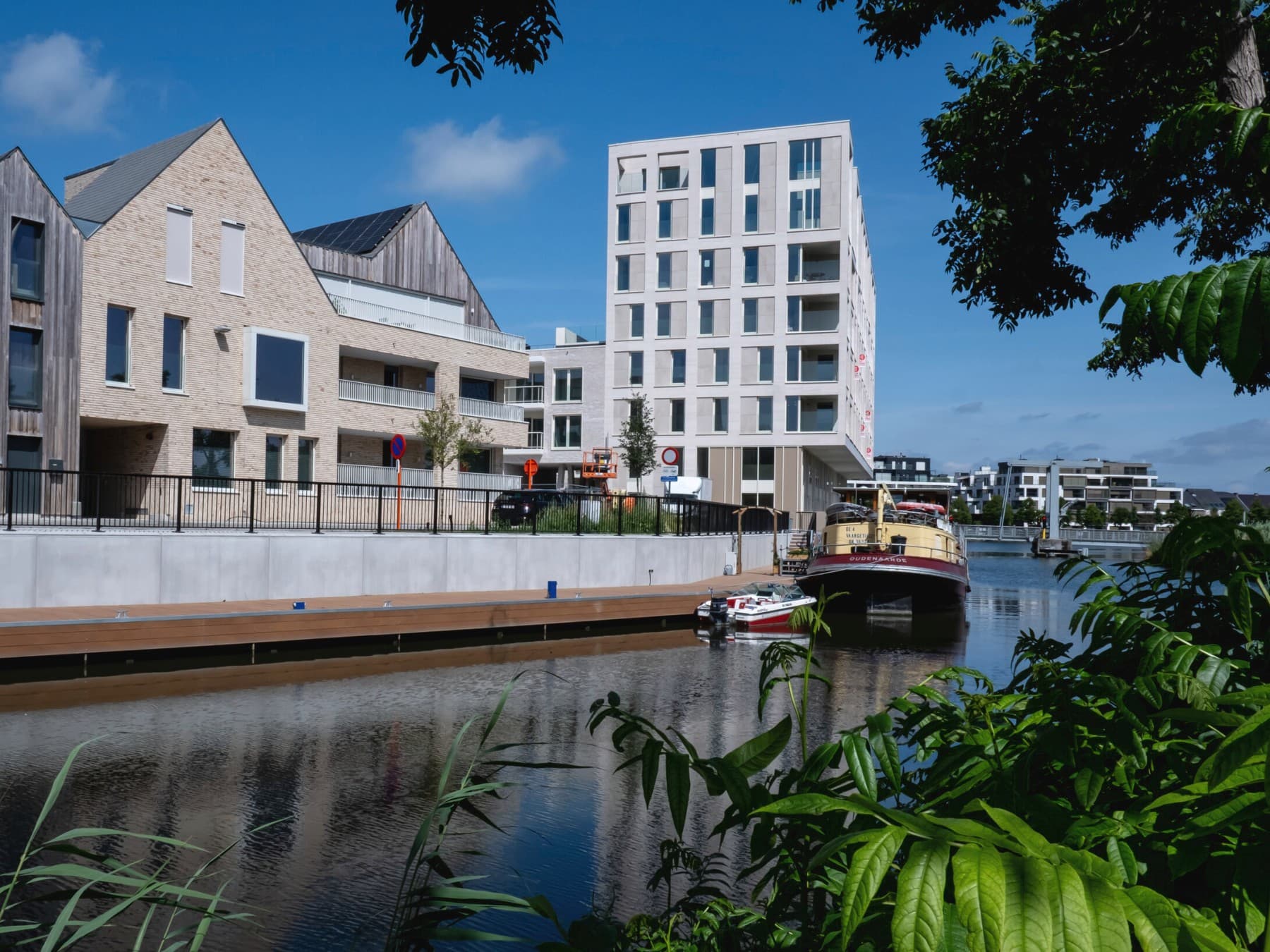 Bord'eau wooncomplex met appartementen langs het water met op de achtergrond een boot.
