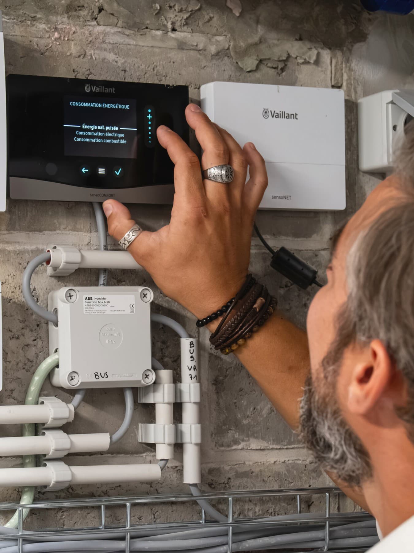 Man past instellingen aan op thermostaat, naast de thermostaat hangt een internetmodule