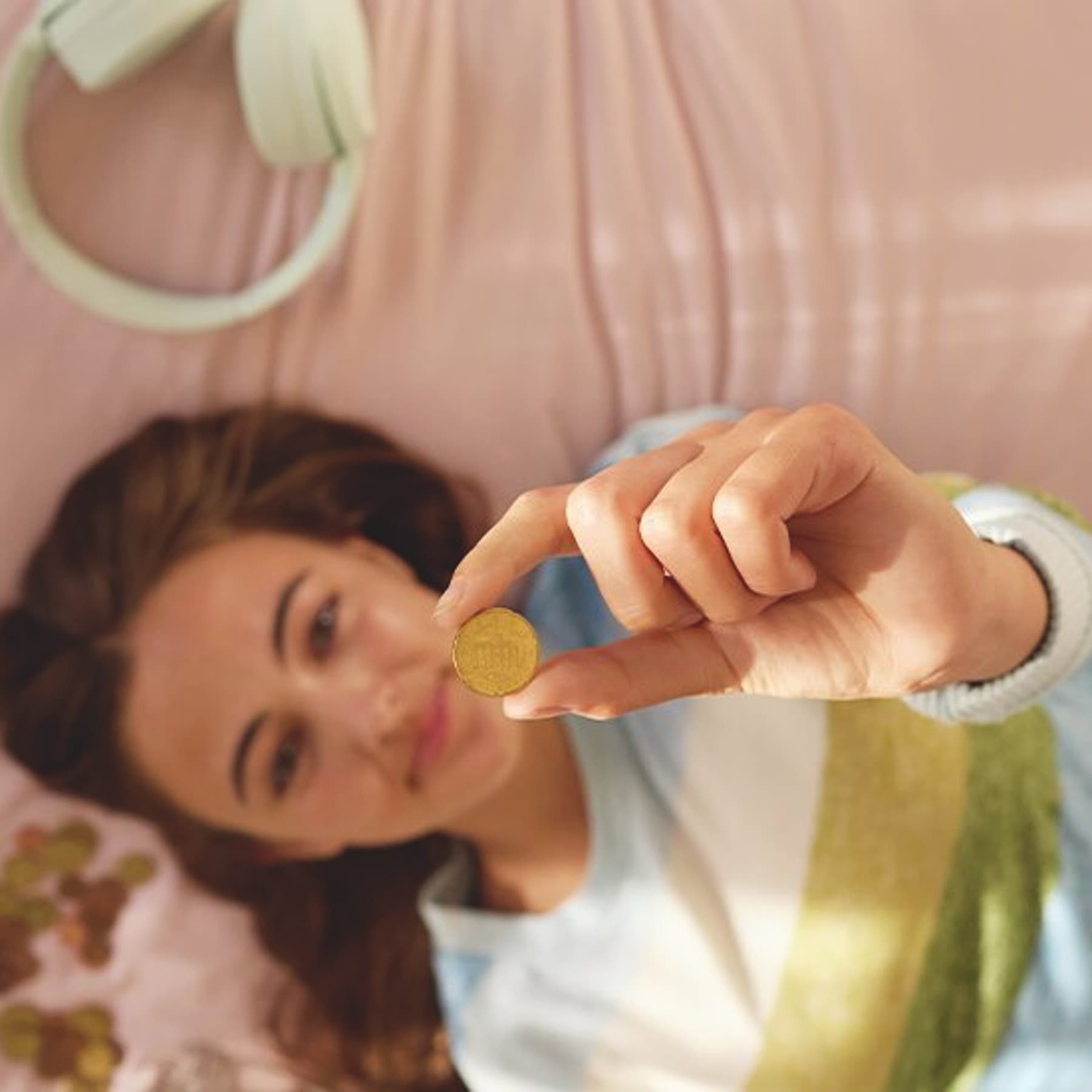 Une femme est allongée sur son lit et tient une pièce de monnaie