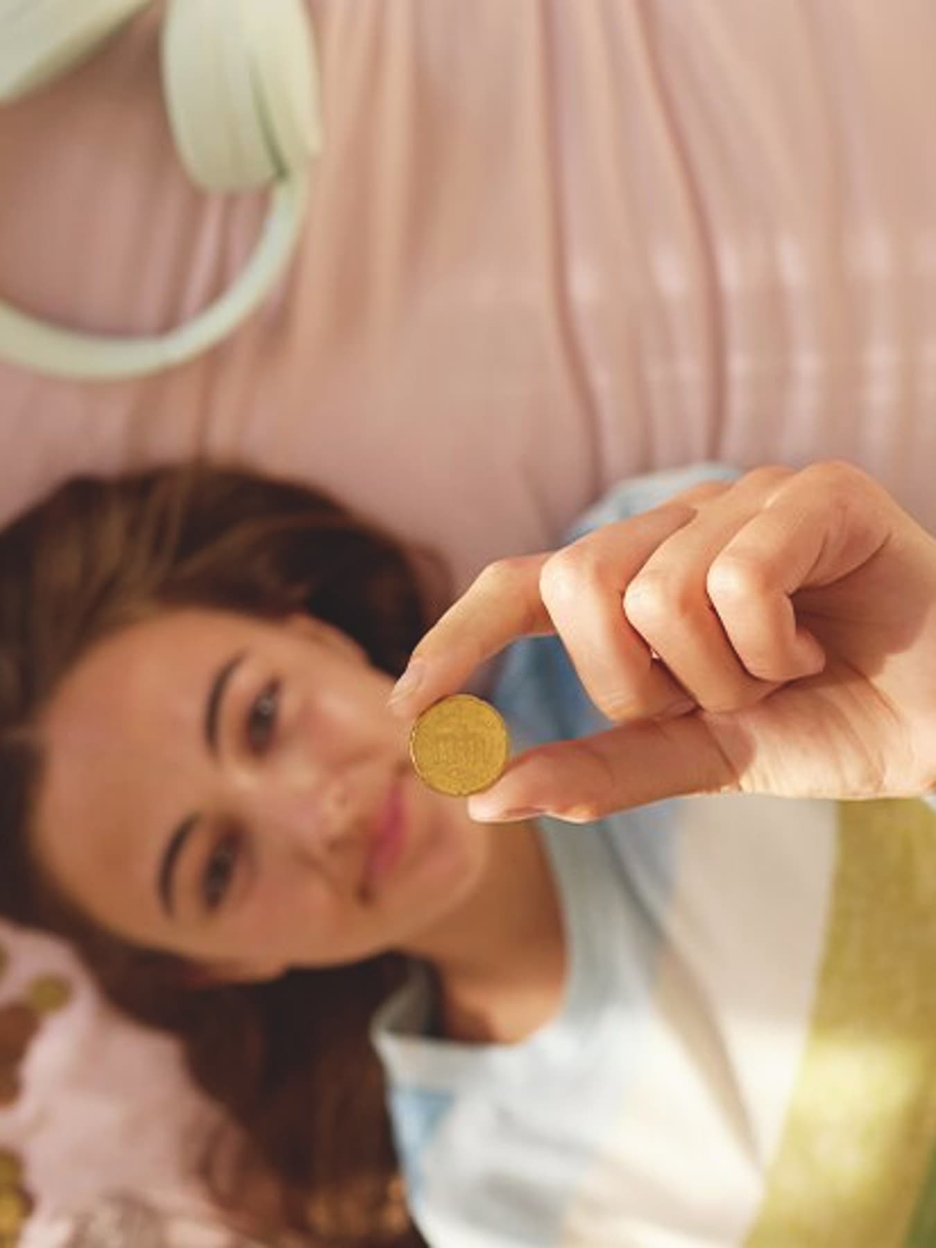 Vrouw ligt op bed en houdt een munt in de lucht