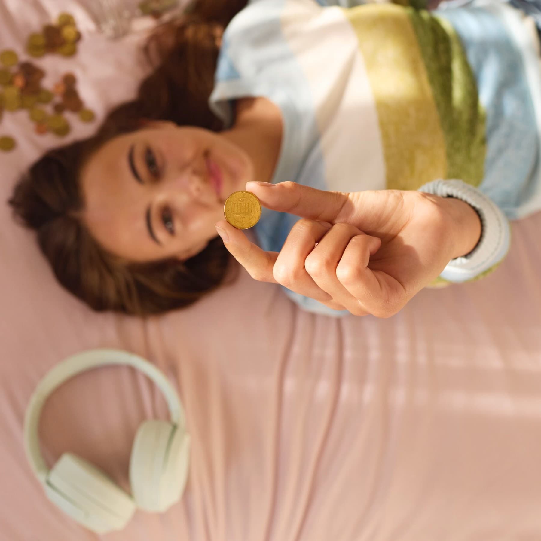 Vrouw ligt op bed en houdt een muntstuk vast