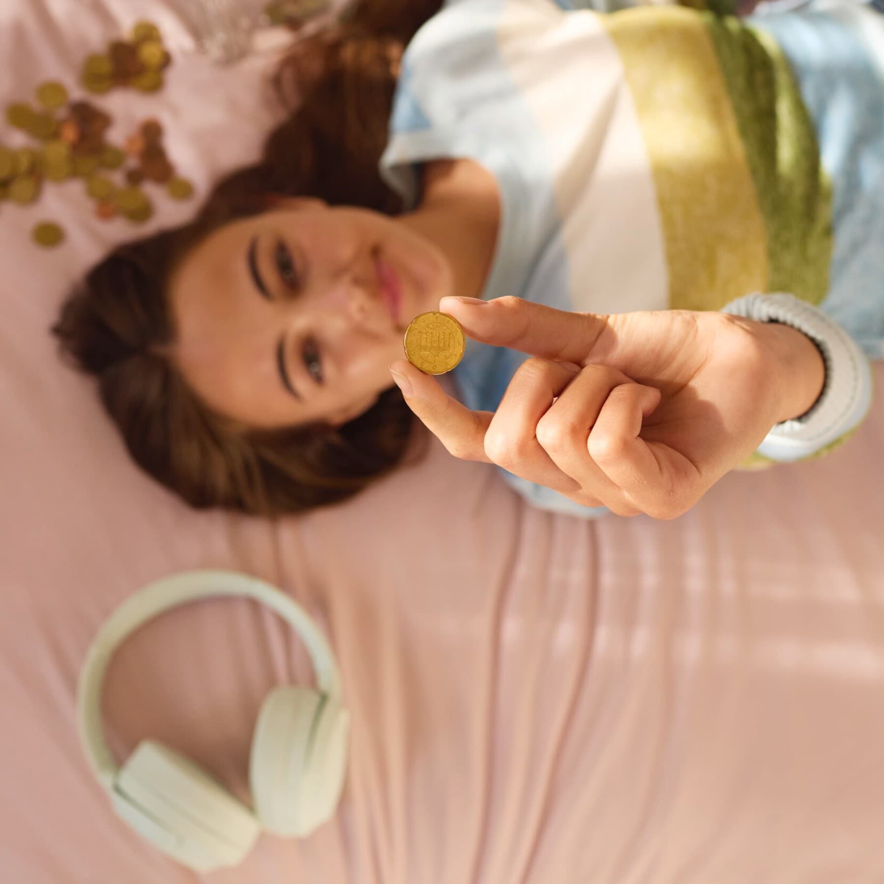 Vrouw ligt op haar bed en houdt een muntstuk vast