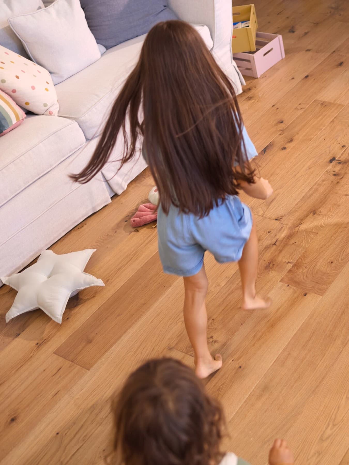 twee kinderen die thuis op blote voeten over een houten vloer rennen