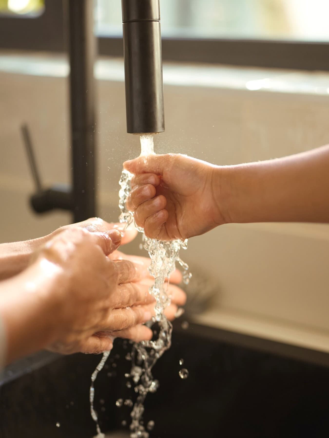 Vrouw en kind houden hun handen onder stromend water