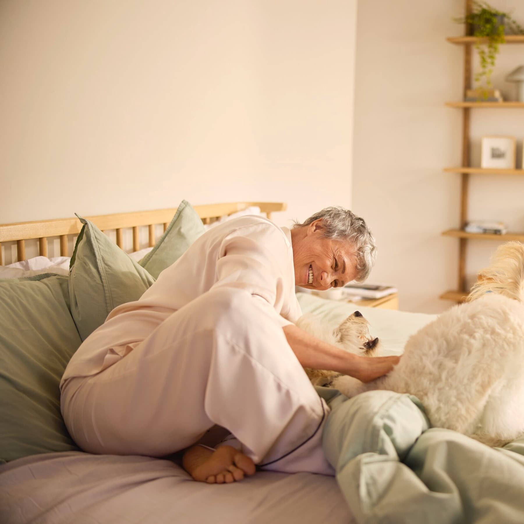 Een glimlachende vrouw die een hond op het bed aait