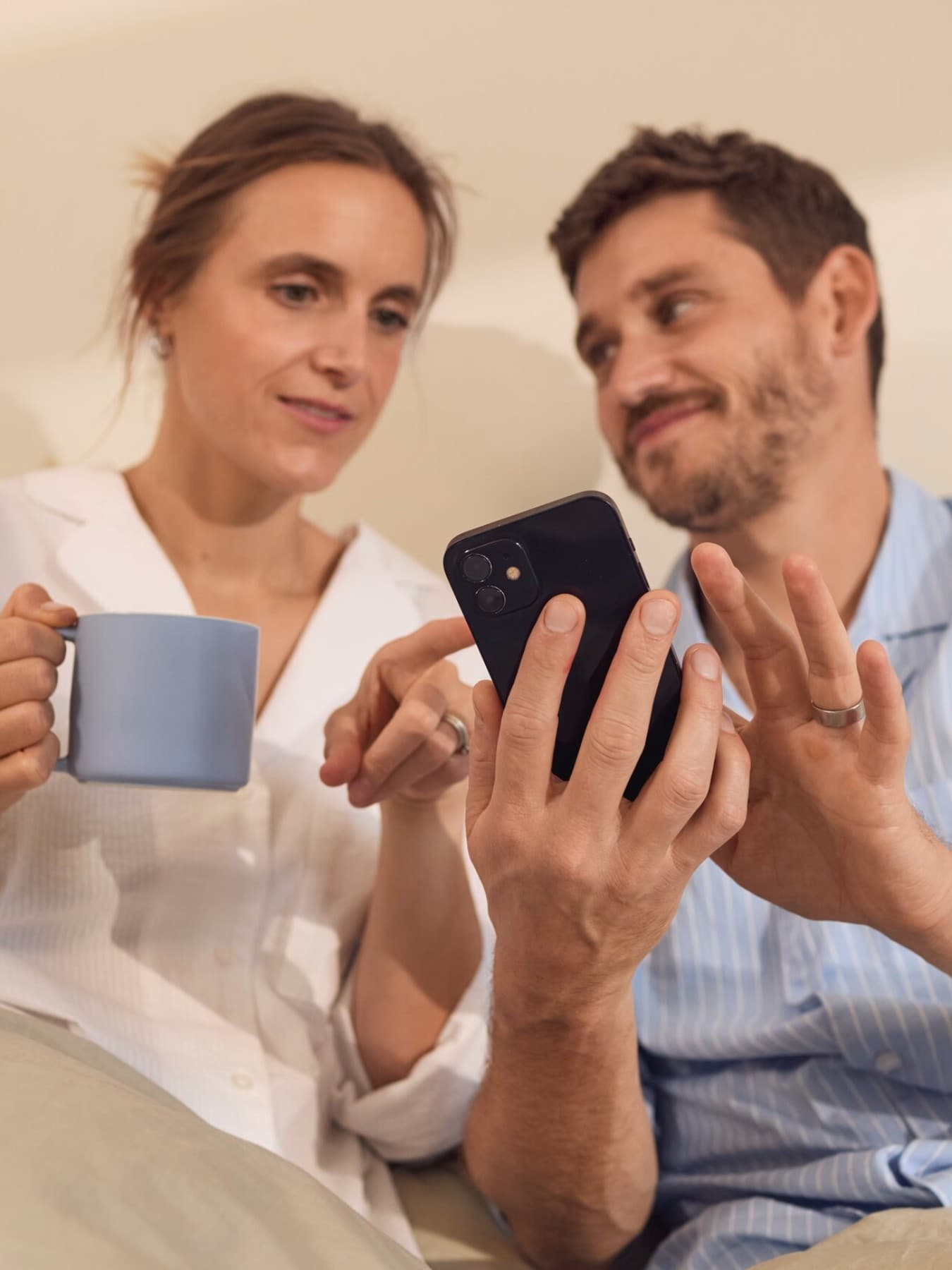 Koppel zit in bed en typt op smartphone
