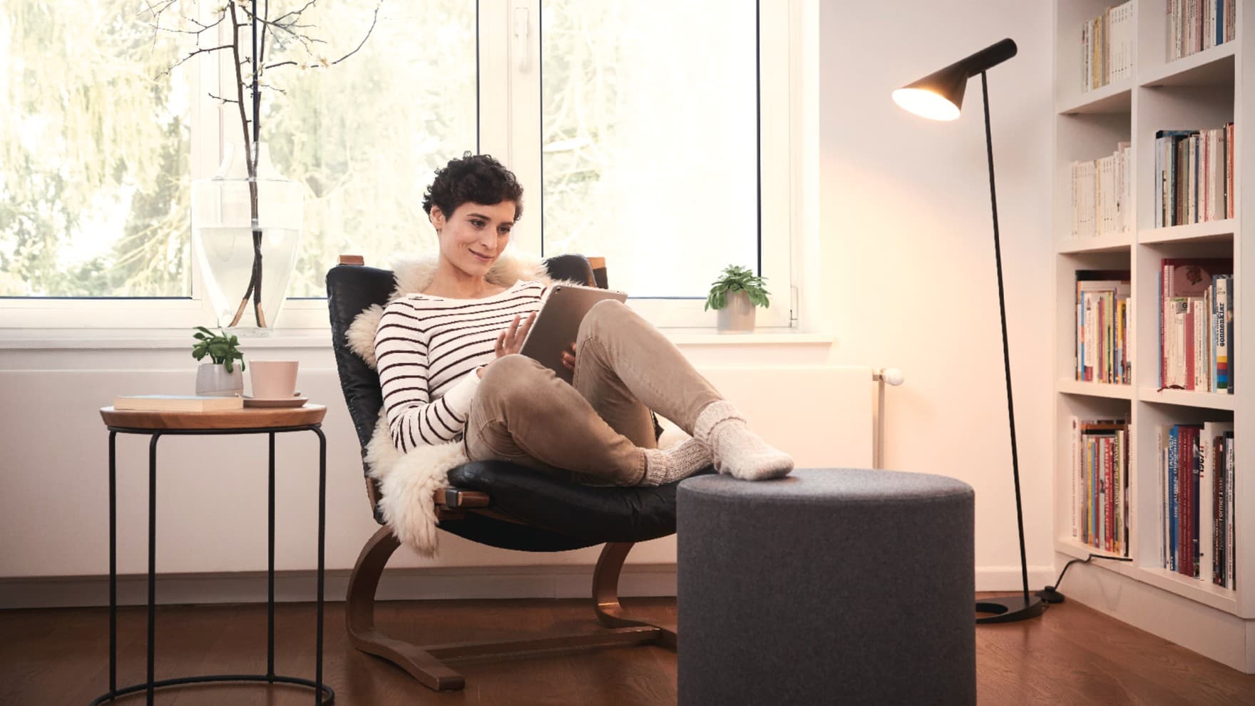 Vrouw zit in een fauteuil en leest op haar tablet
