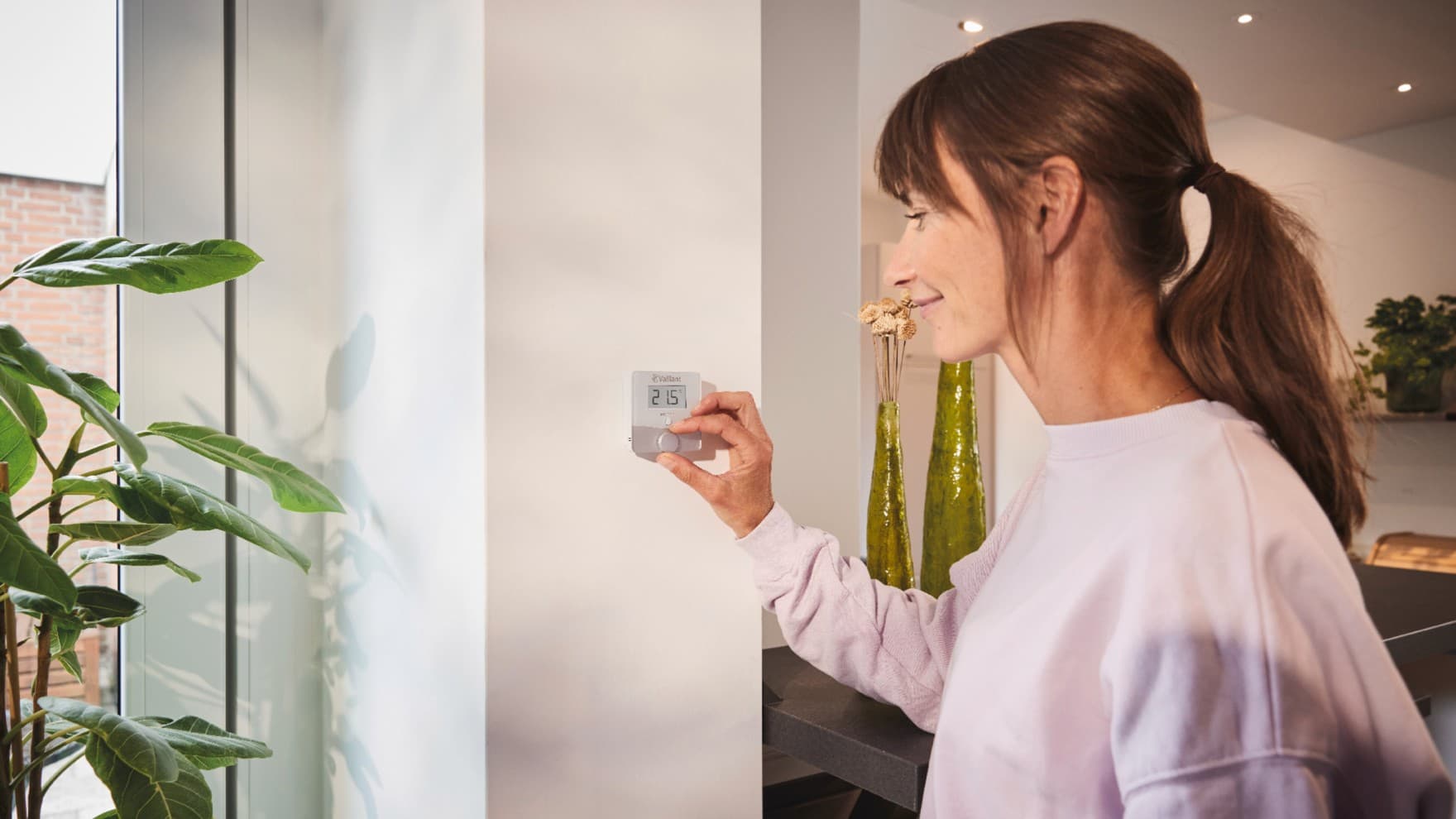 Een vrouw die de Vaillant sensoROOM-thermostaat gebruikt