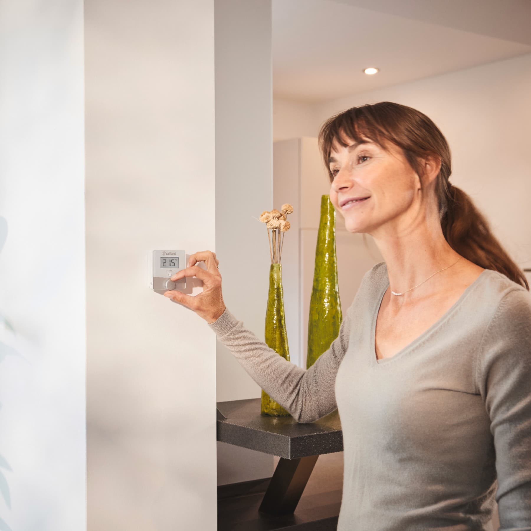 Vrouw die een thermostaat aan de muur aanzet