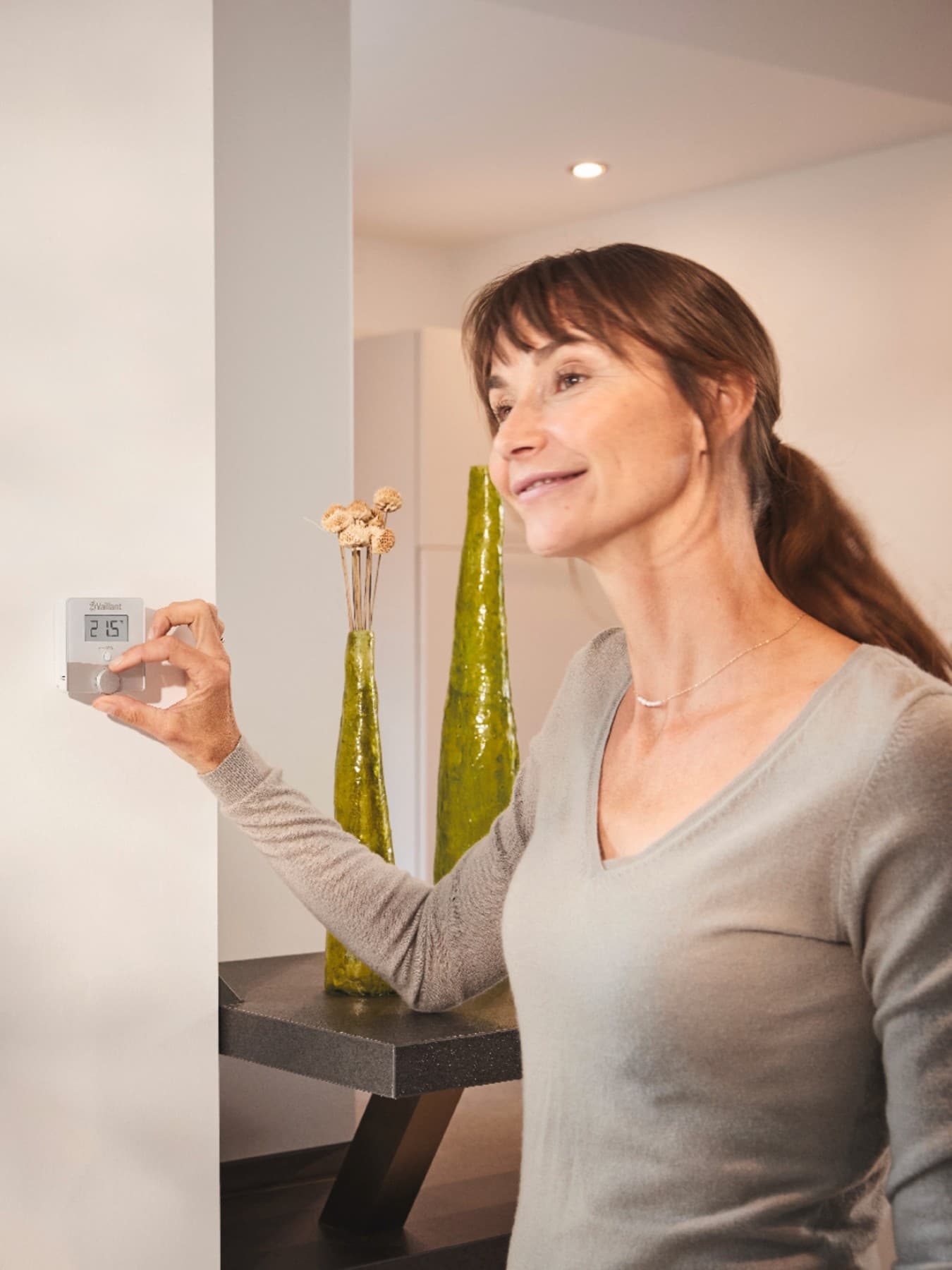 Vrouw die een thermostaat aan de muur aanzet