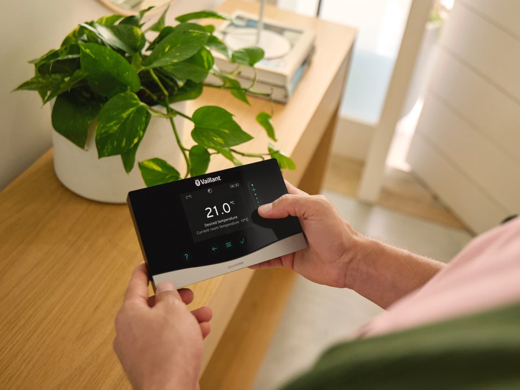 Man met de systeemregelaar sensoCOMFORT in zijn hand