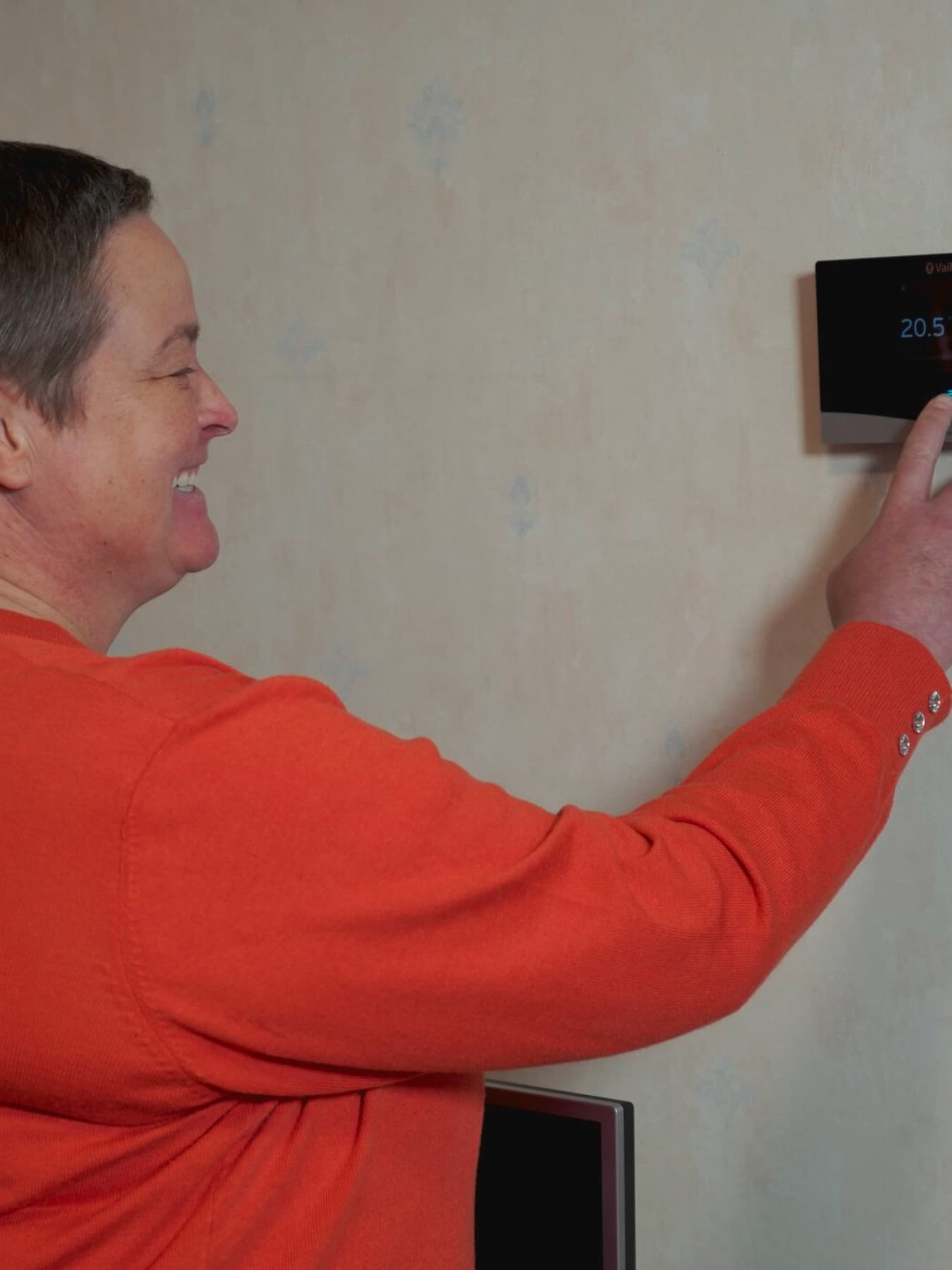 Klant Anke past instellingen aan op een thermostaat op de muur