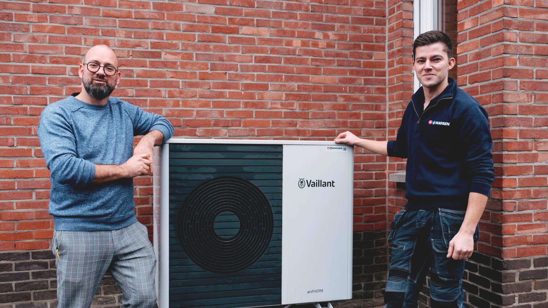 Klant en installateur staan naast buitenunit van een warmtepomp