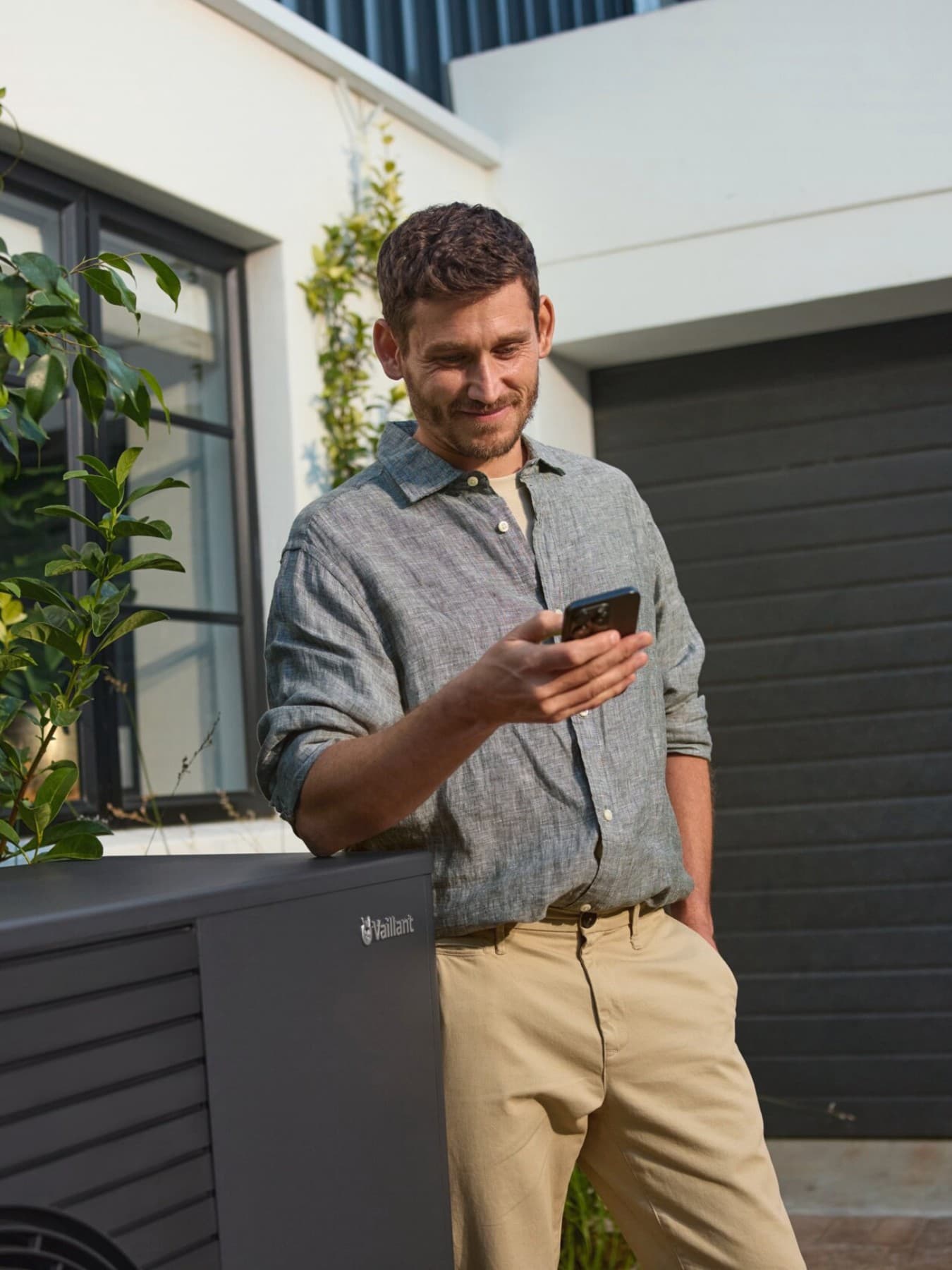 Man met smartphone naast warmtepomp | Vaillant