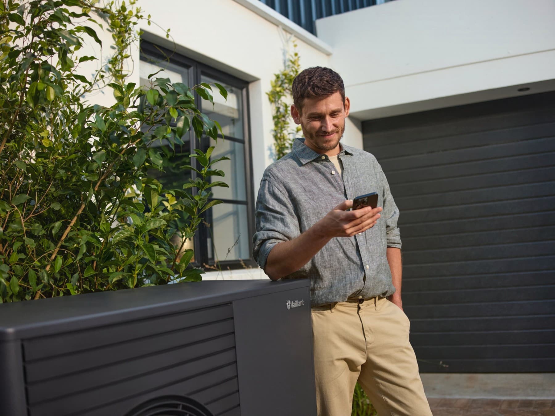 Man met smartphone naast warmtepomp | Vaillant