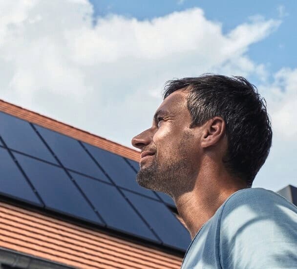 Een man die voor een zonnepaneelinstallatie op het dak staat