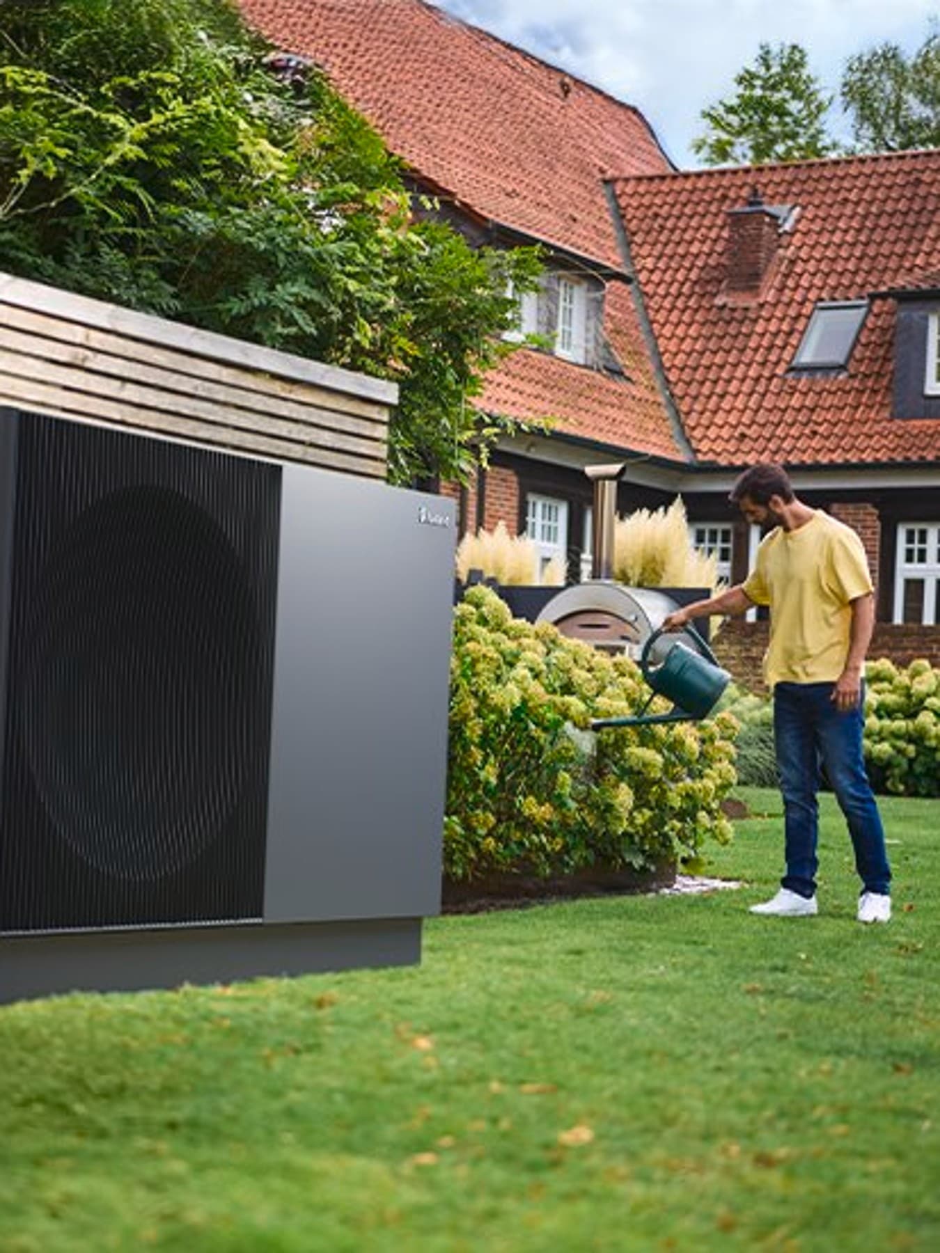 aroTHERM perform warmtepomp in een tuin terwijl een man water geeft aan bloemen