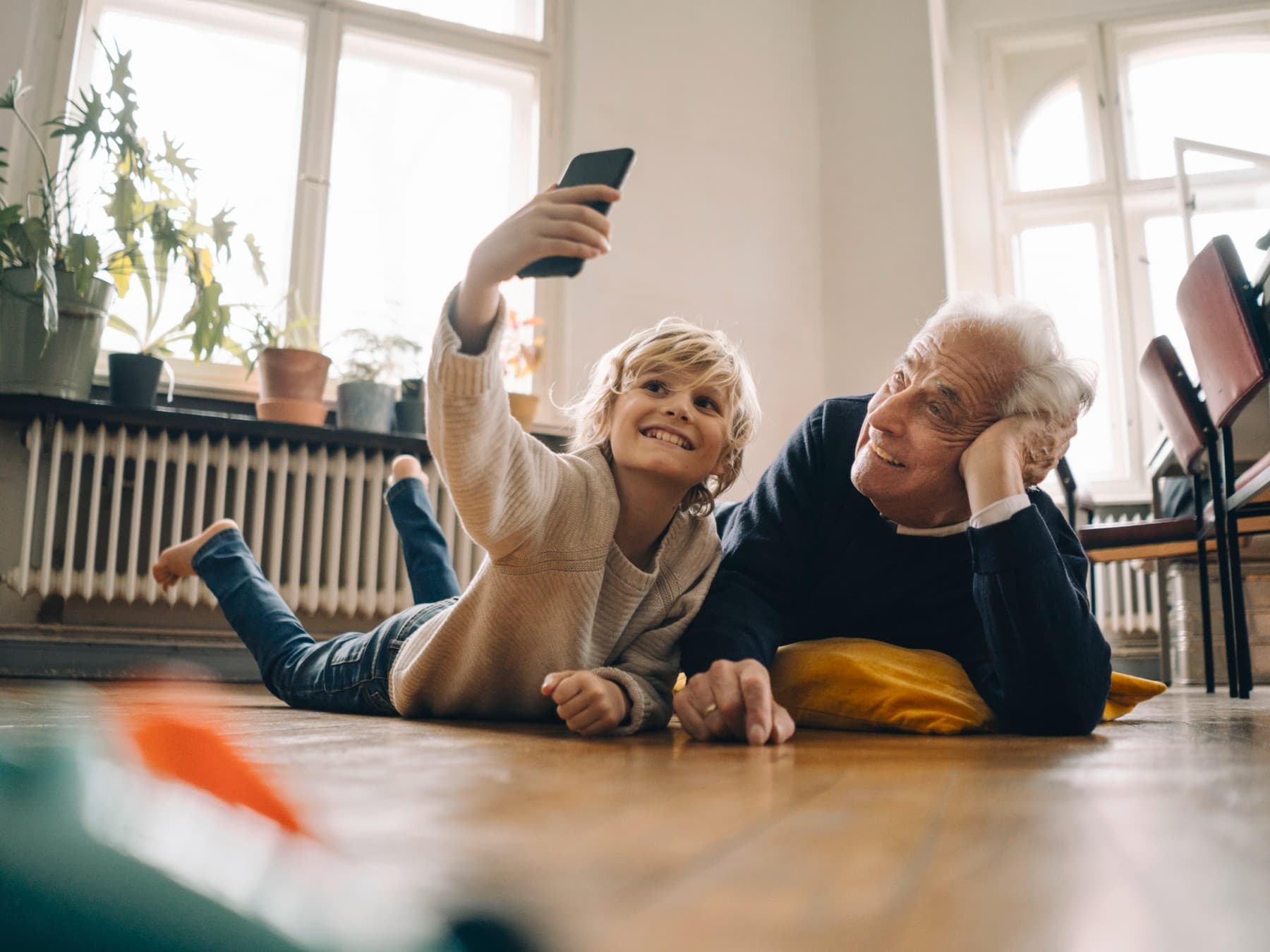 Man en kind liggen op de vloer en kijken op smartphone