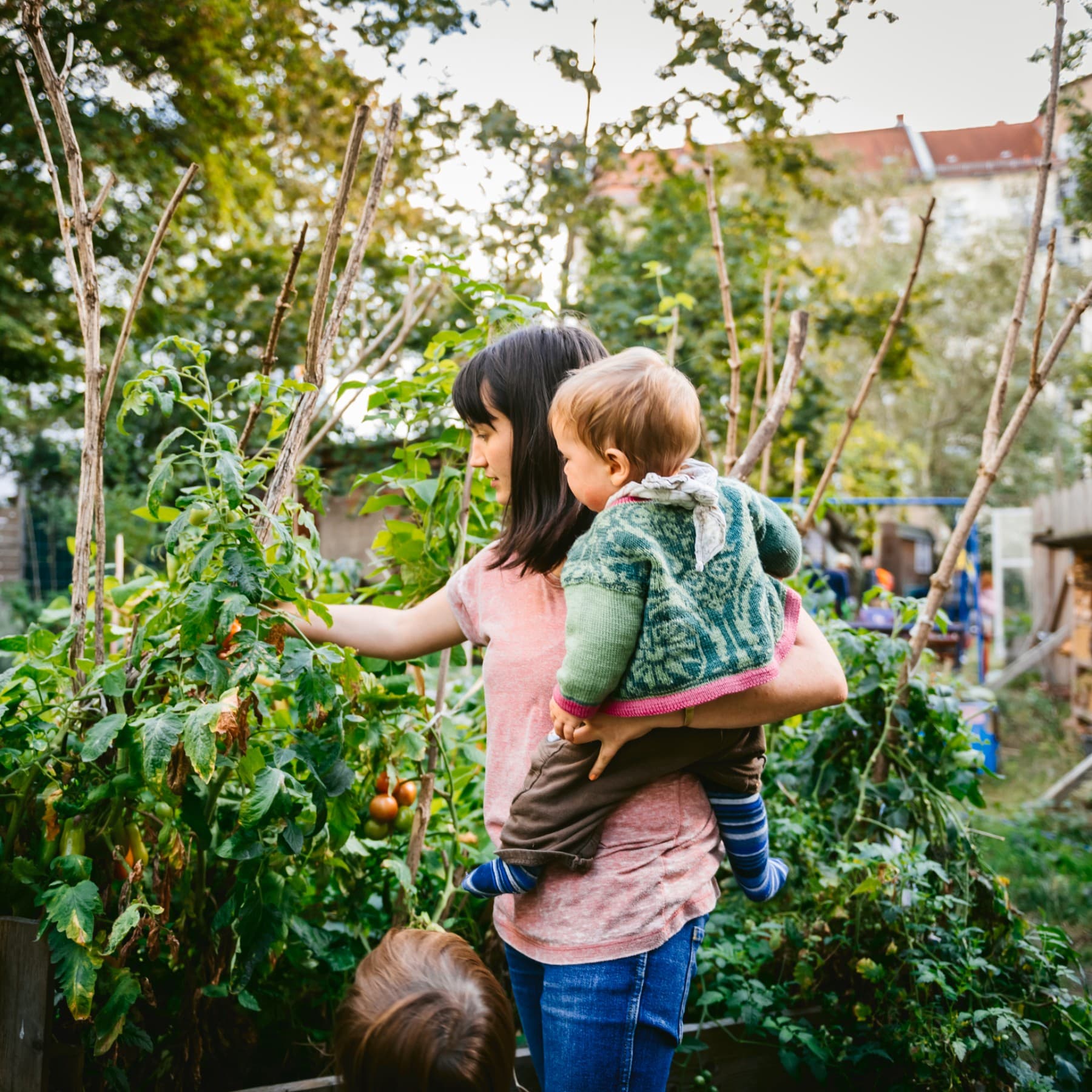Vrouw met kind op haar arm in moestuin