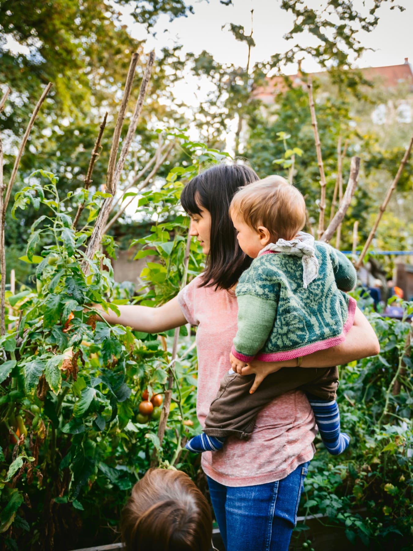 Vrouw met kind op haar arm in moestuin