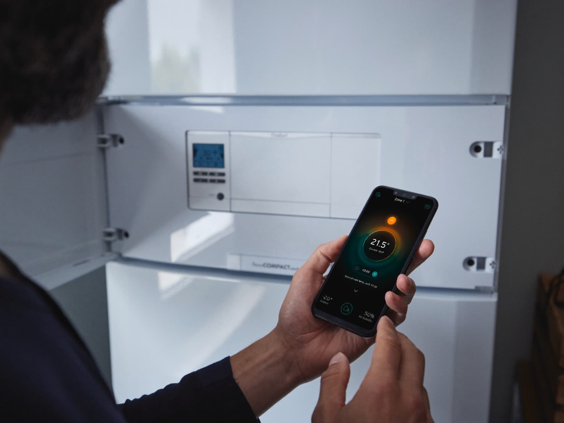 Man stelt temperatuur in op zijn telefoon