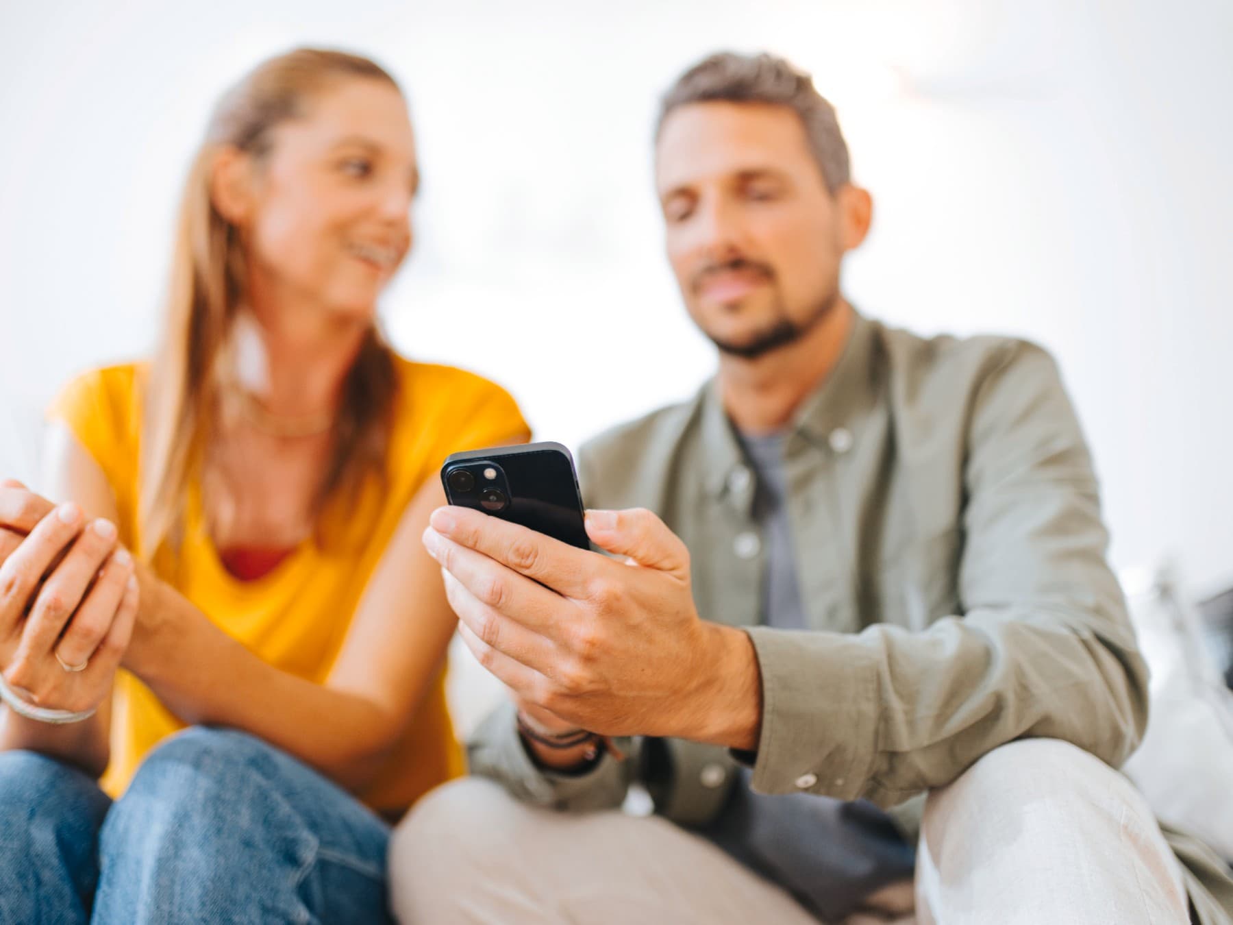 Koppel zit in de zetel en typt op een smartphone