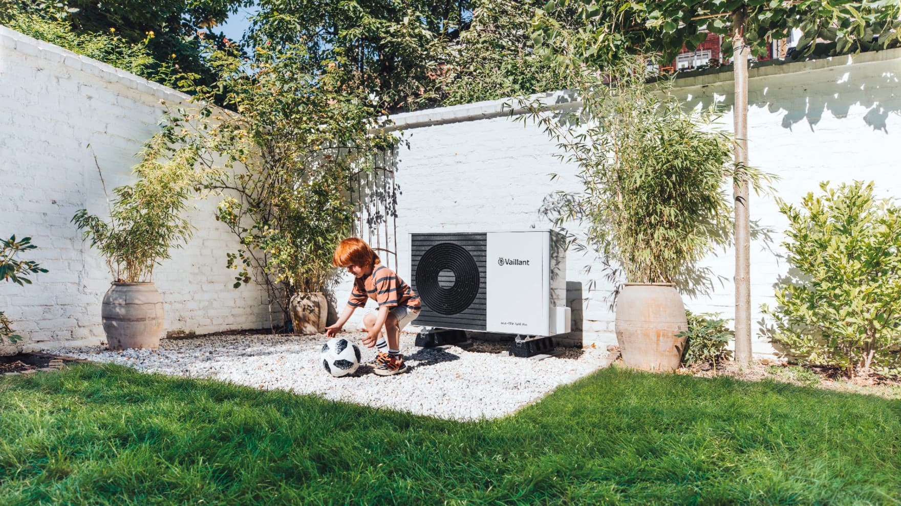 Kind speelt met bal voor een warmtepomp.