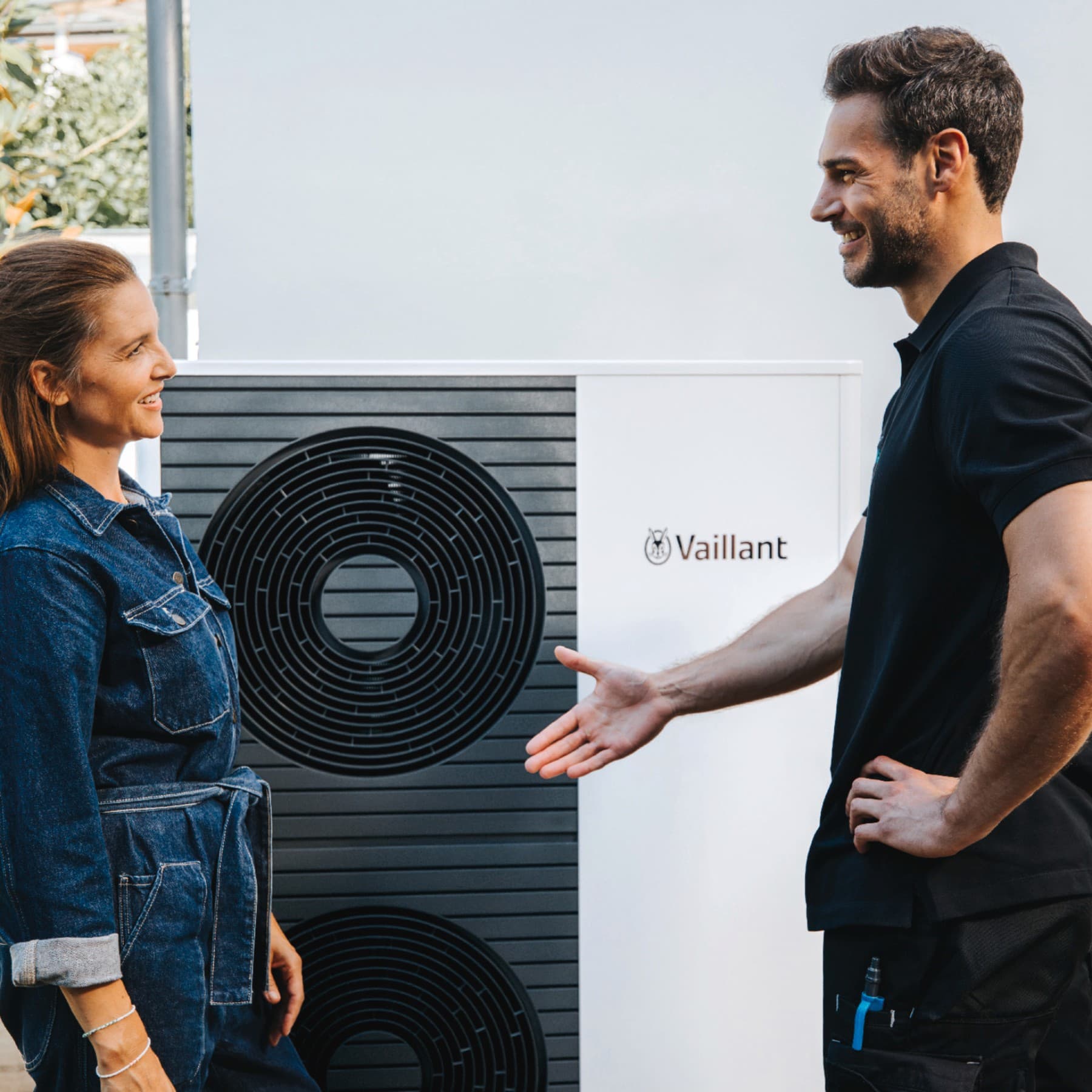 Een vrouw en een monteur van Vaillant die elkaar de hand schudden voor een warmtepomp