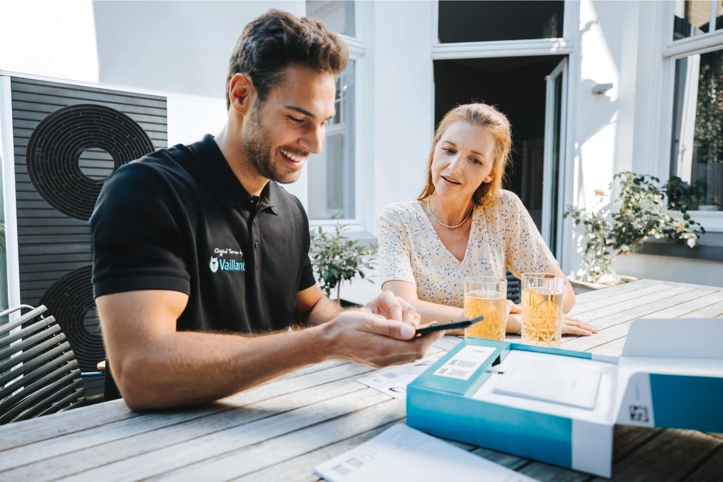 Vaillant-servicetechnieker met een smartphone en een klant naast hem