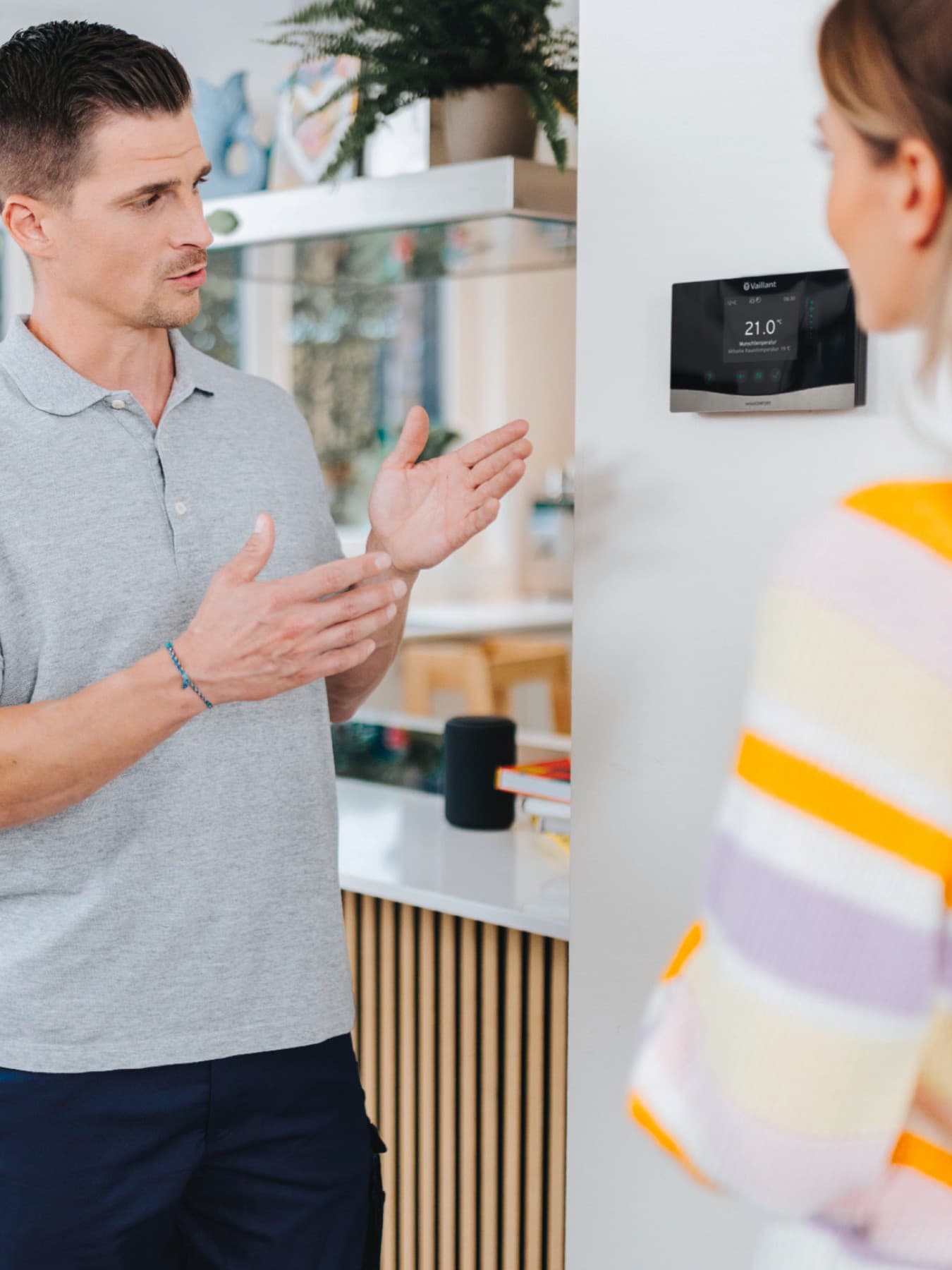installateur die een huiseigenaar een thermostaat aan de muur laat zien