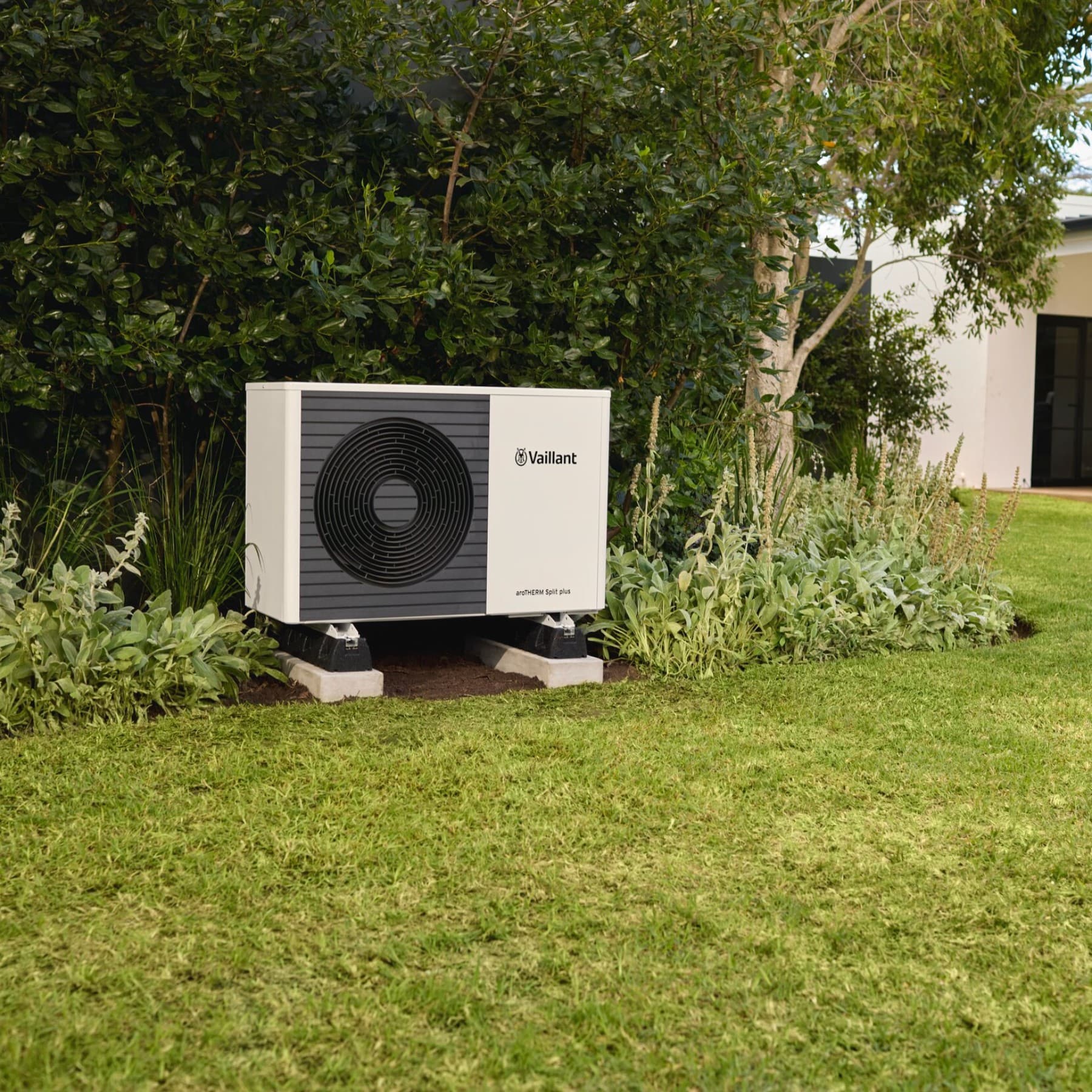 Een buitenunit van een warmtepomp in een tuin