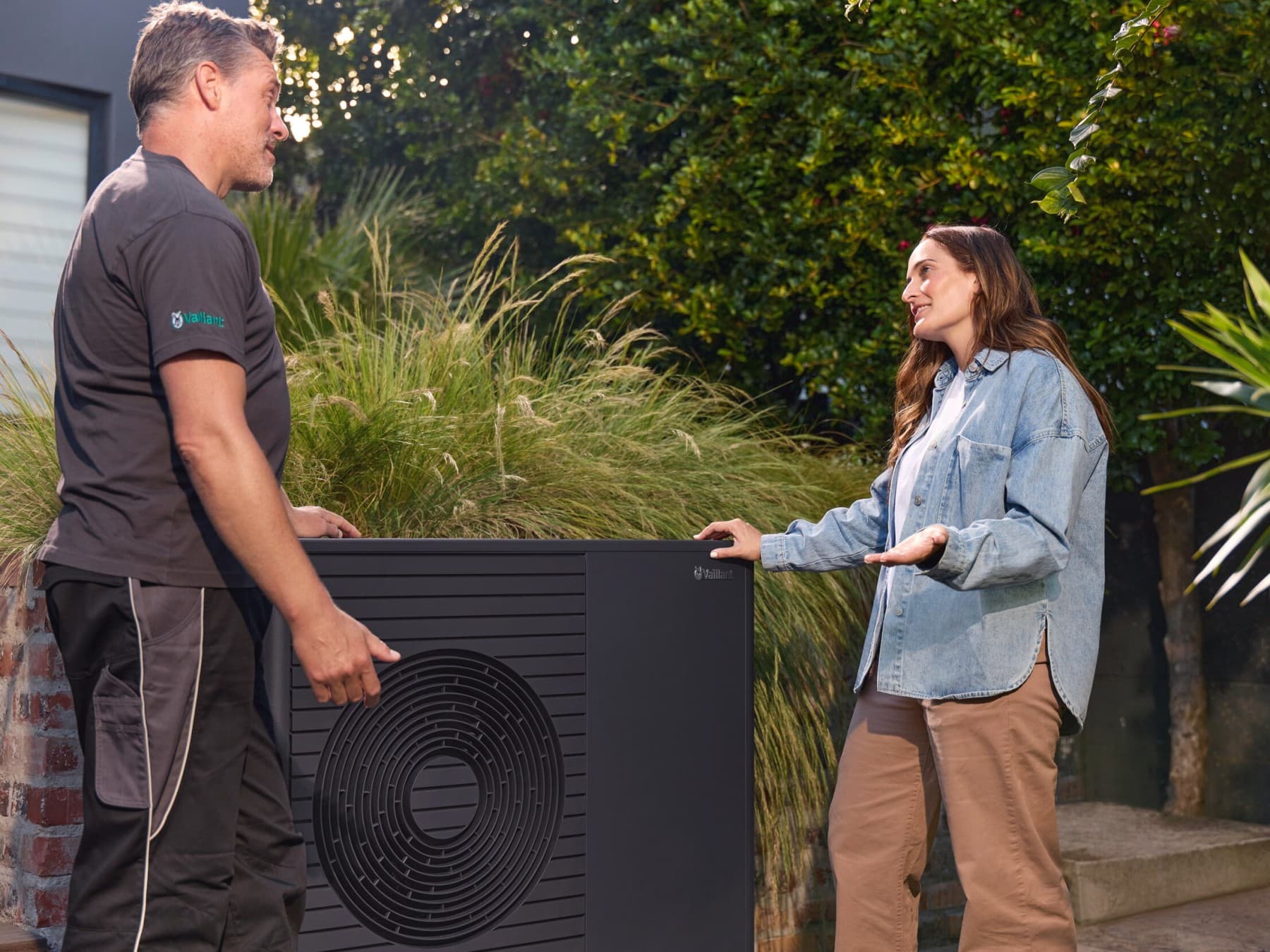 Warmtepompinstallateur en huiseigenaar in gesprek naast een warmtepomp