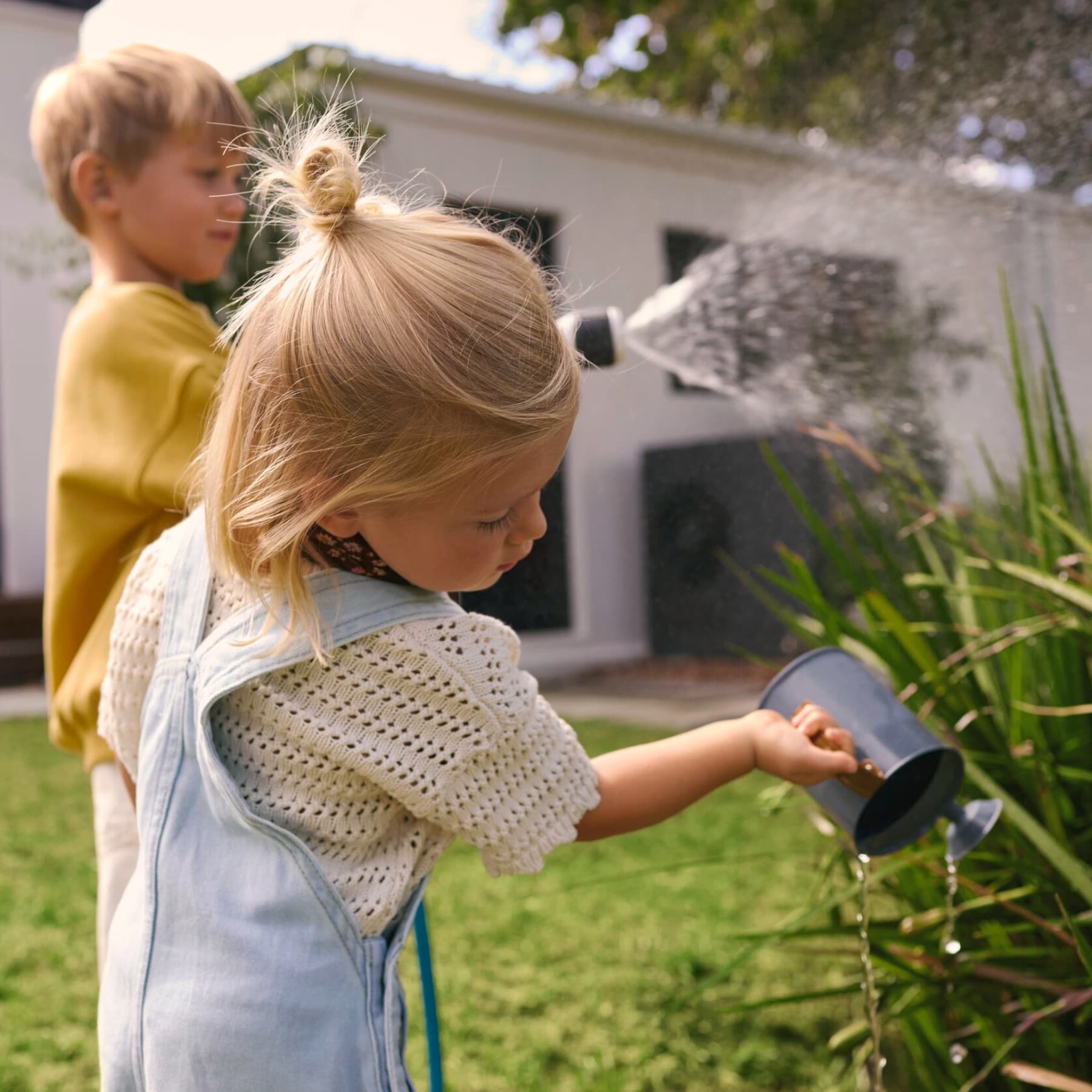 Kinderen geven planten water met een gieter