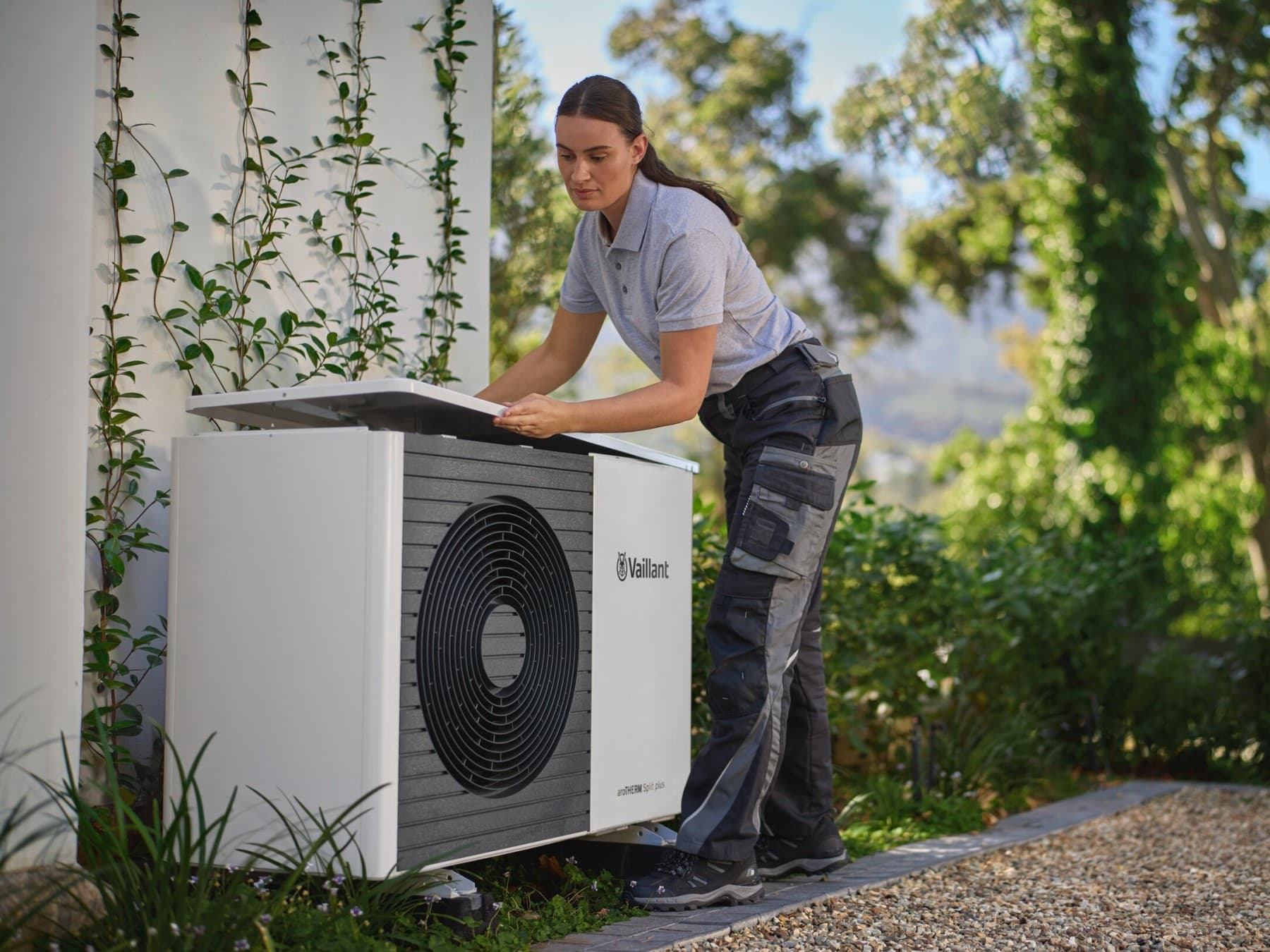 Vrouw heft het bovenste deel van een witte warmtepomp op