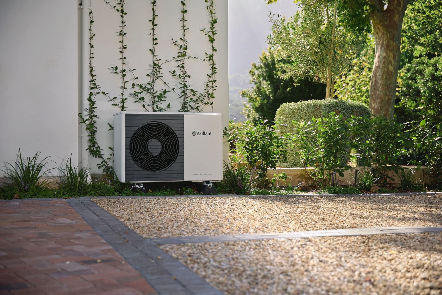 Warmtepomp buitenunit, staande voor een muur in een tuin