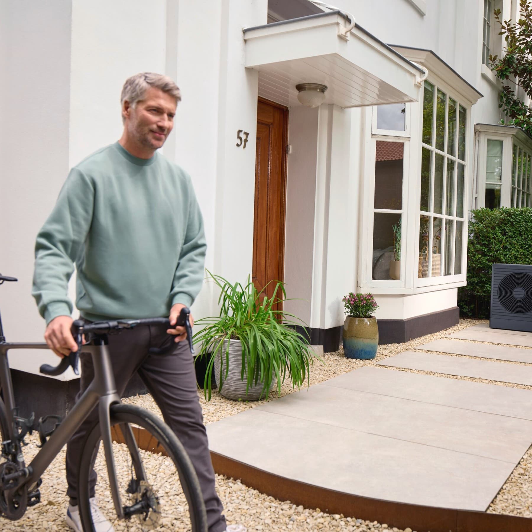 Man met fiets en warmtepomp op de achtergrond