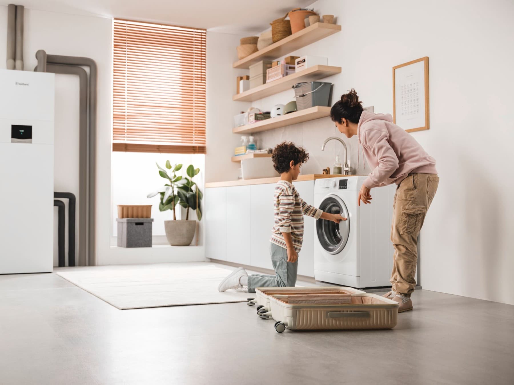 Moeder en zoon bekijken de wasmachine, met op de achtergrond een aardwarmtepomp