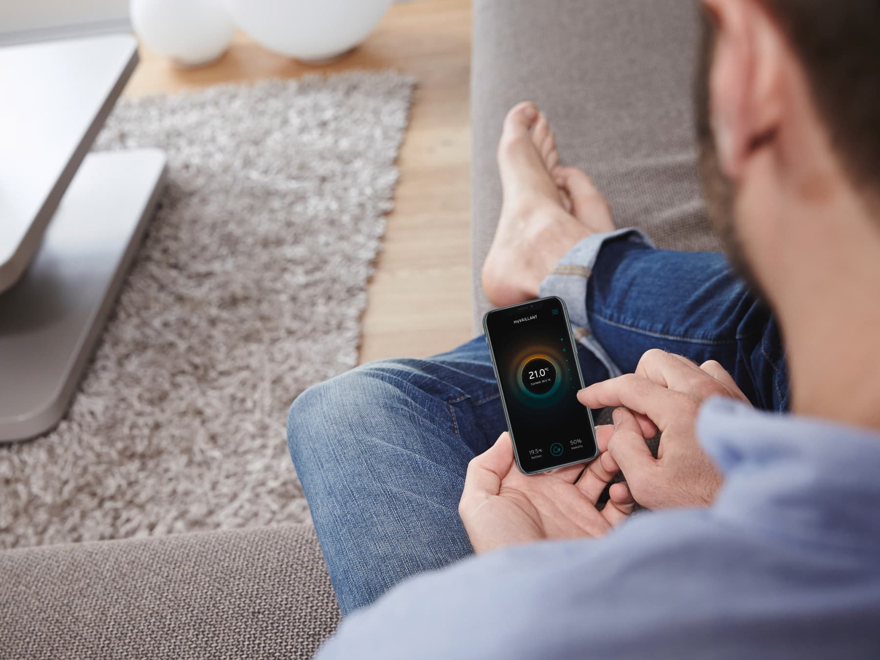 Man zit in de zetel op zijn myVaillant-app