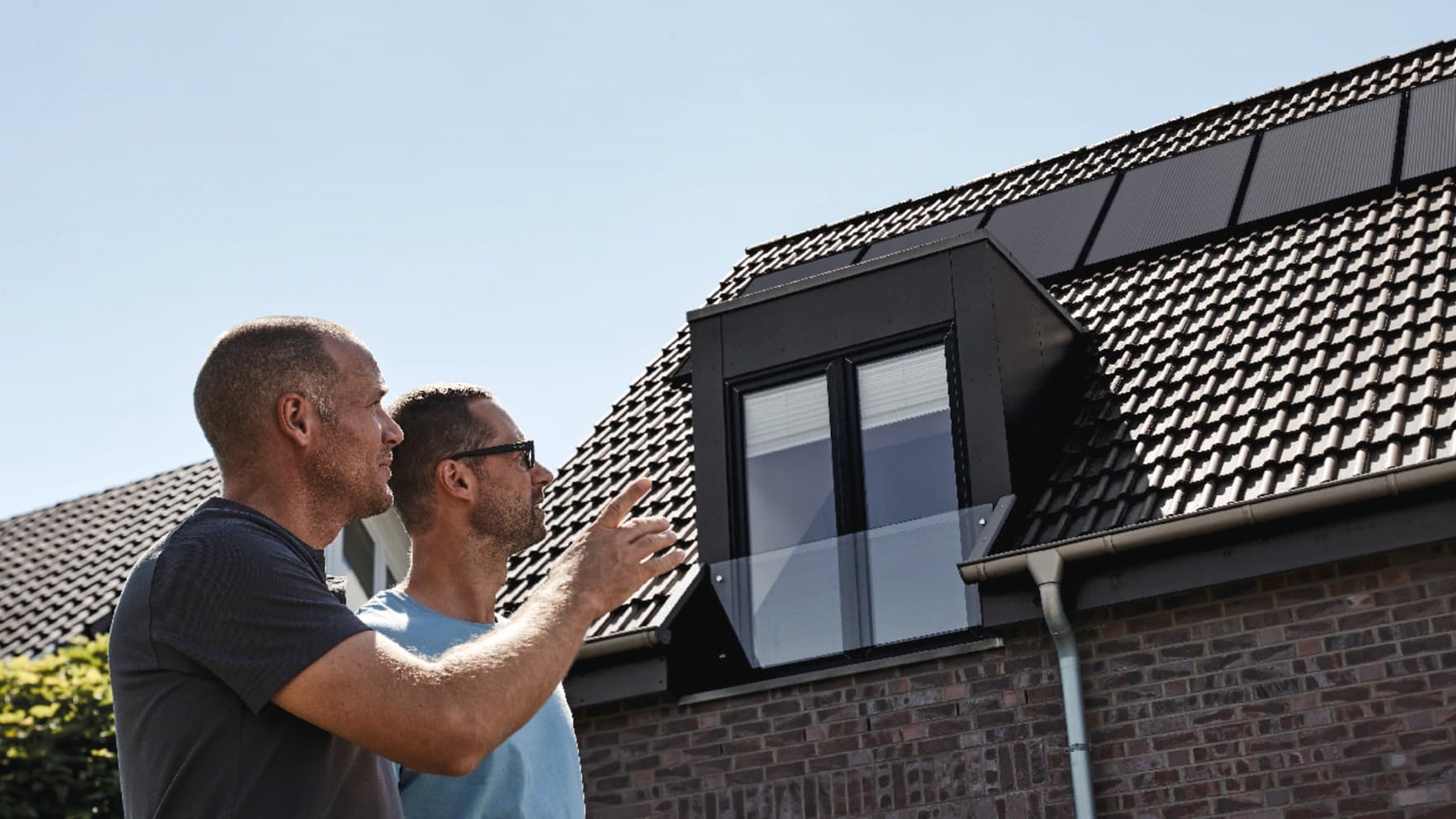 Vakmensen en de huiseigenaar inspecteren het gerenoveerde dak.