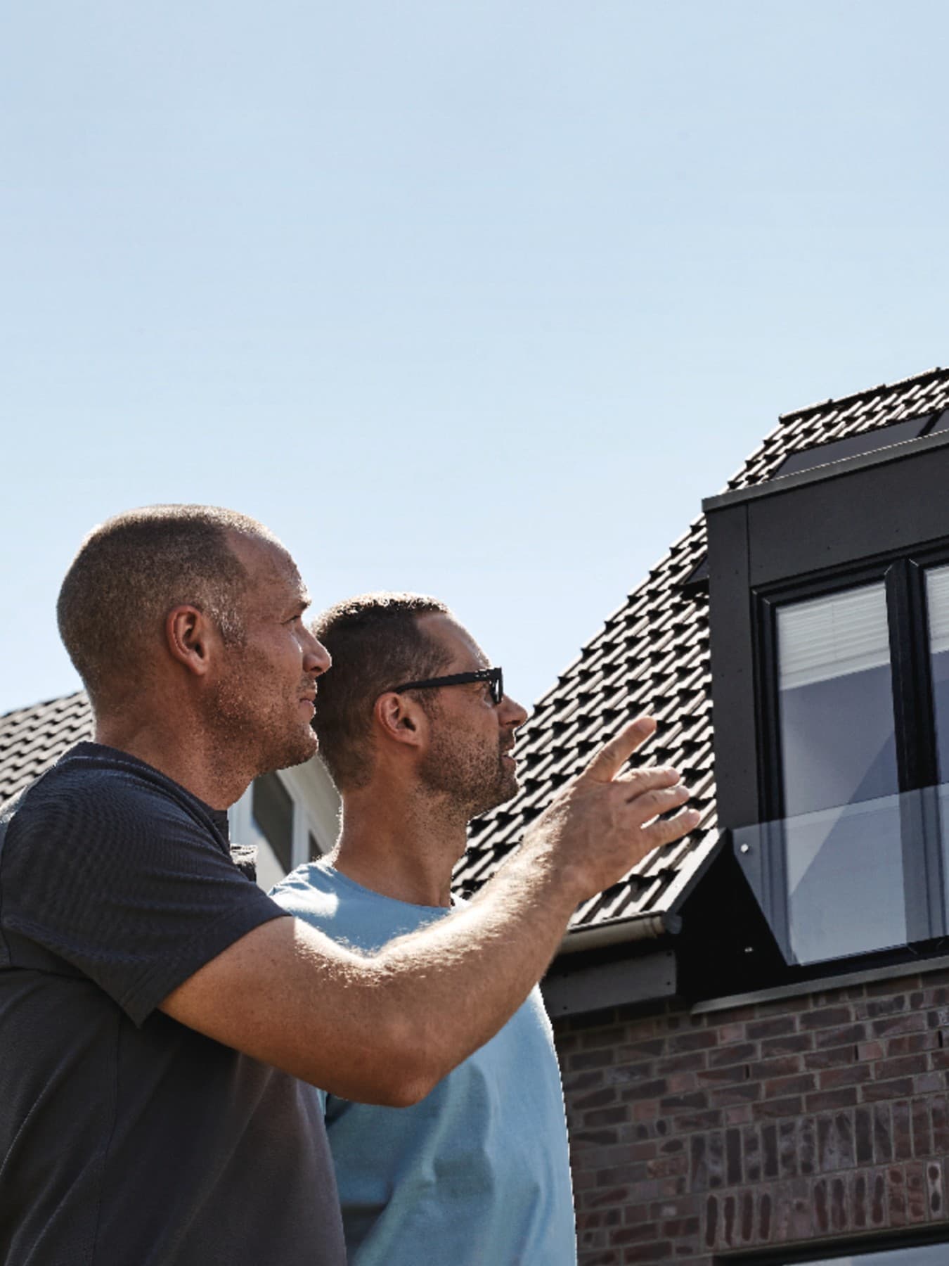 Vakmensen en de huiseigenaar inspecteren het gerenoveerde dak.