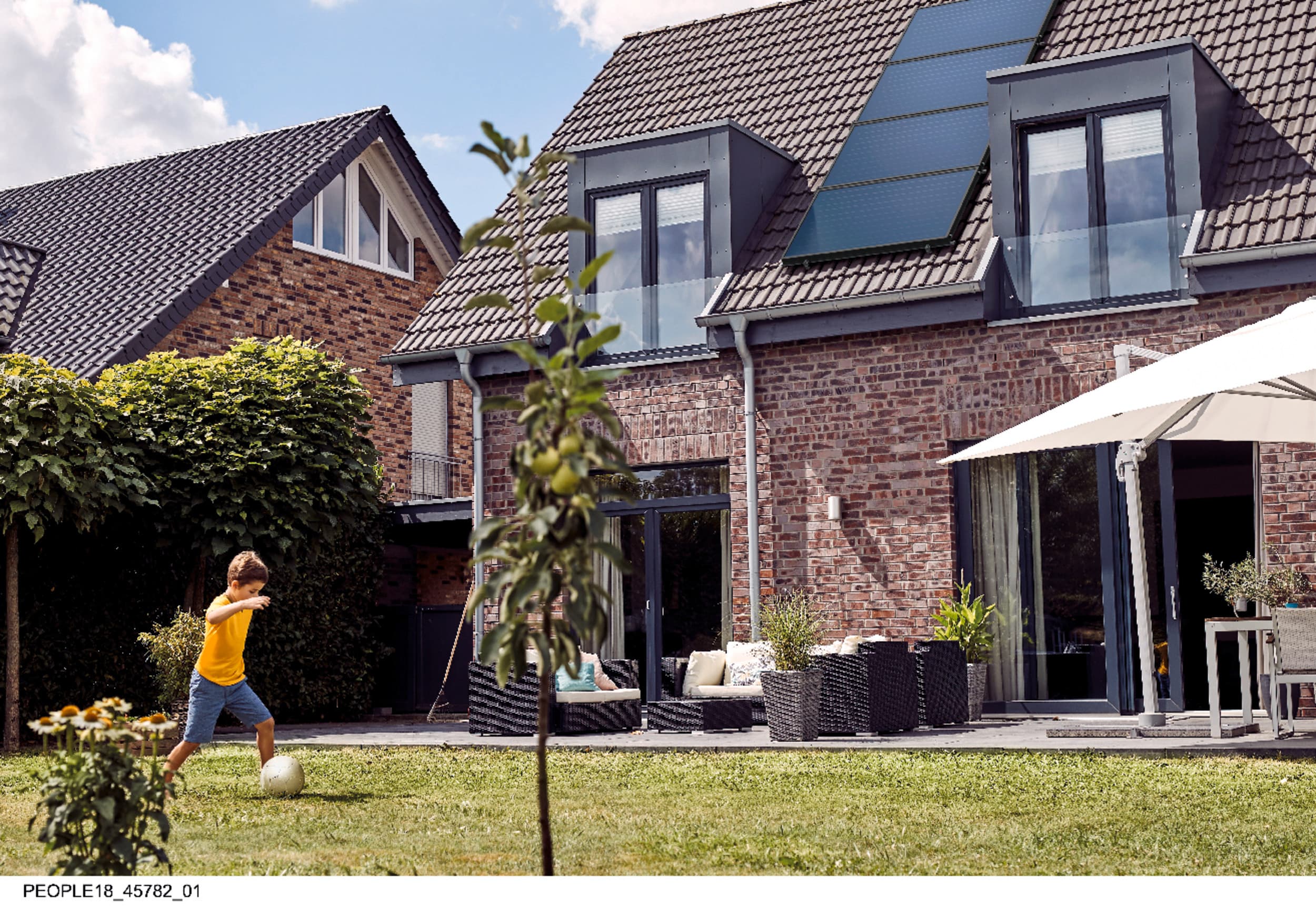 Jongen speelt in de tuin, op de achtergrond zie je een dak met zonnepanelen