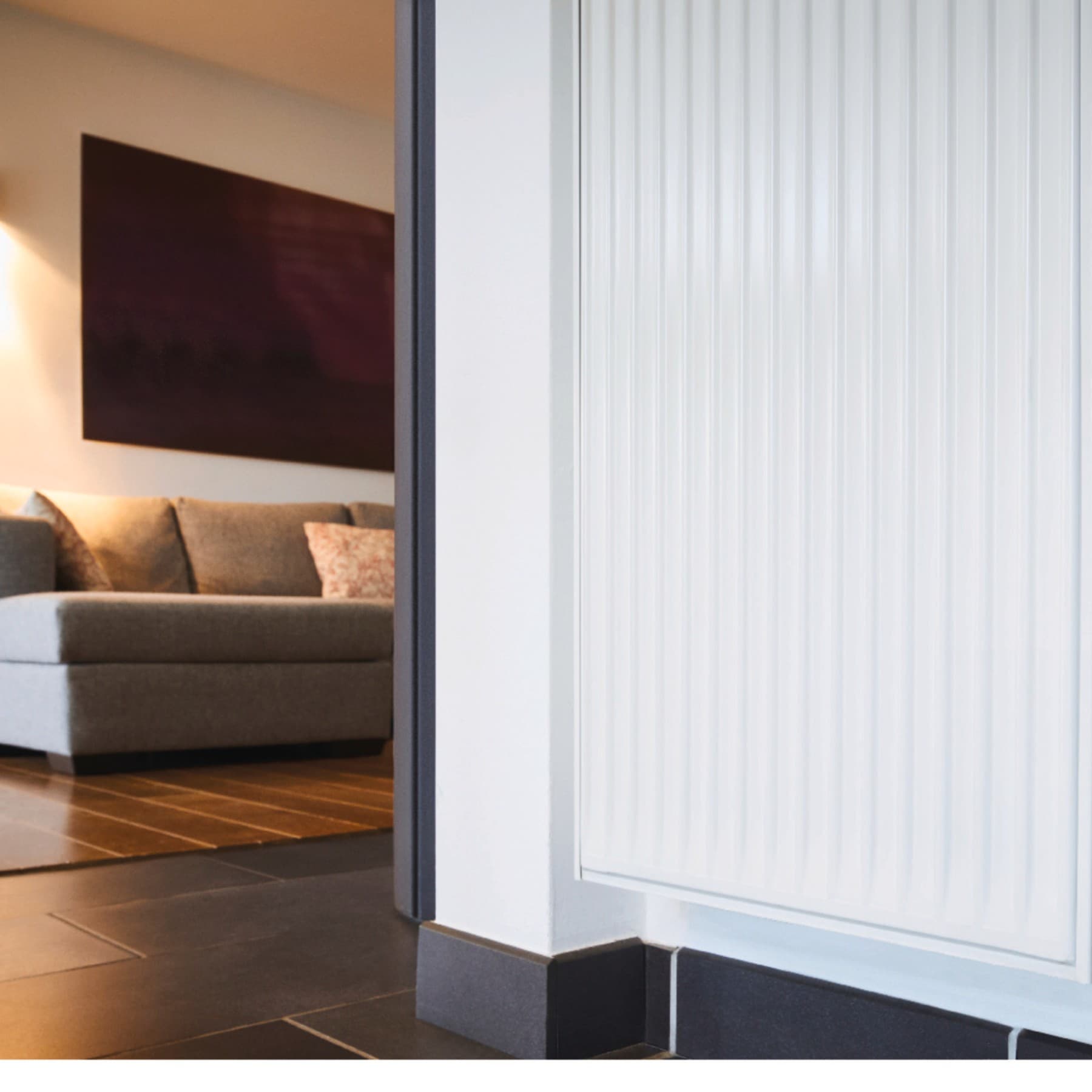 n radiator met op de achtergrond een bank en sfeervolle verlichting; op het display van de radiator staat 21°.