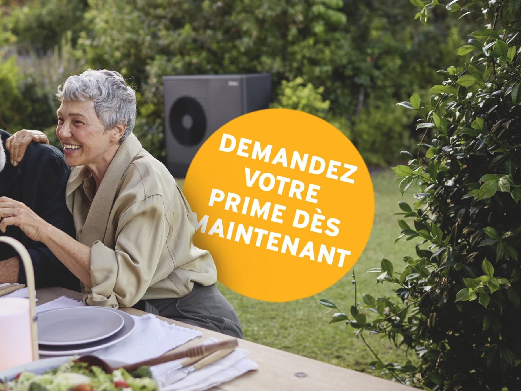 Un couple déjeune en terrasse; une pompe à chaleur est visible en arrière-plan.