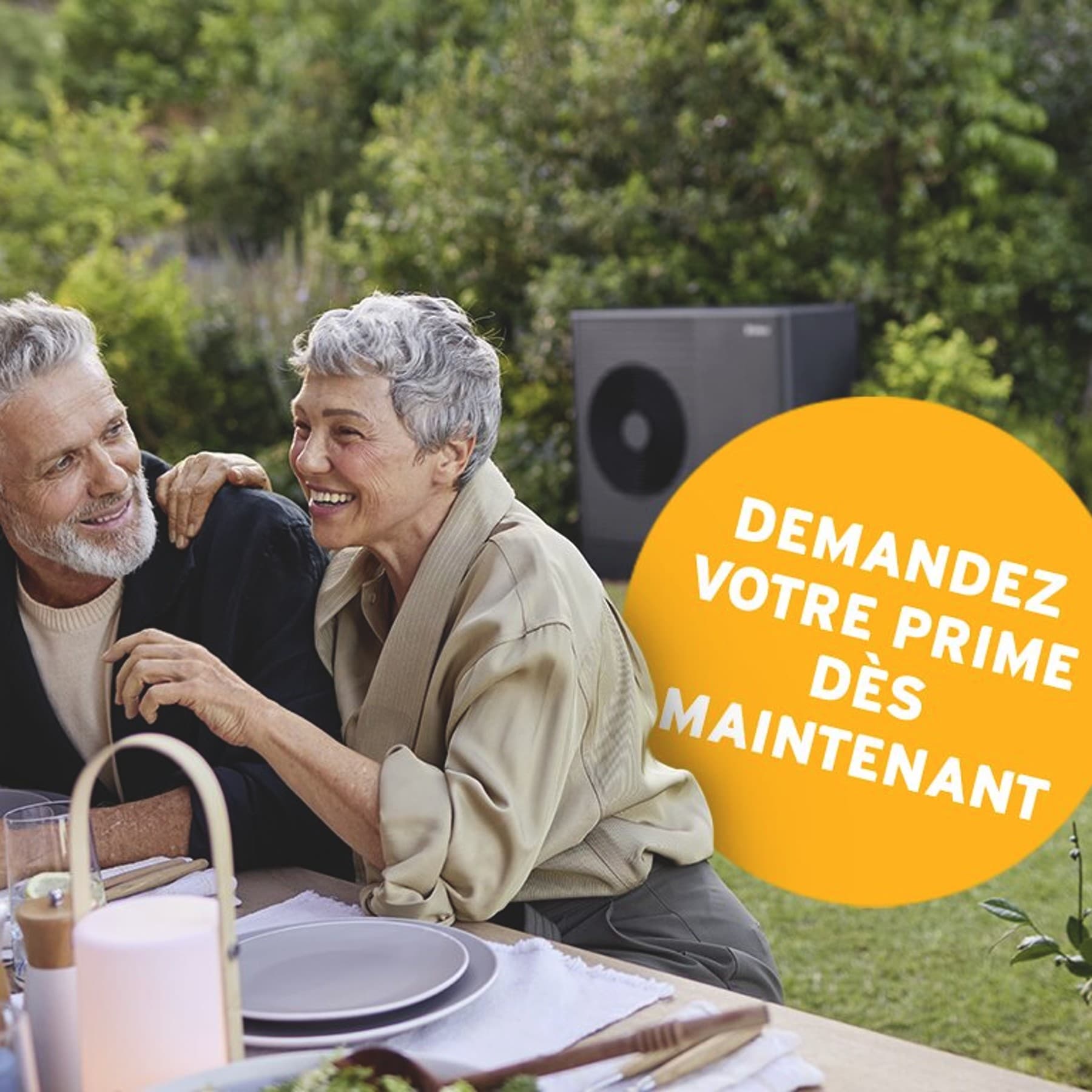 Un couple déjeune en terrasse; une pompe à chaleur est visible en arrière-plan.