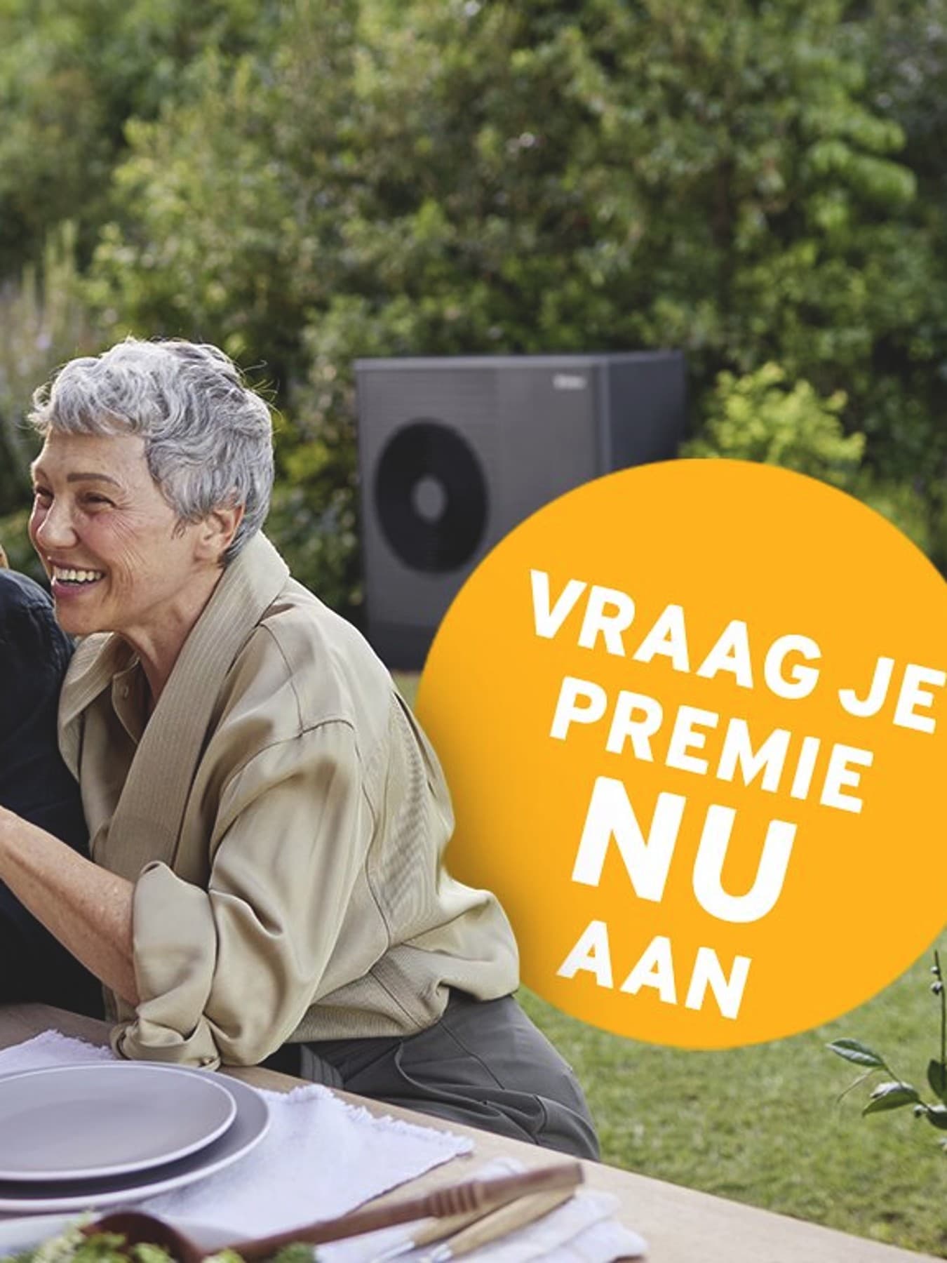 Een stel zit op het terras te eten; op de achtergrond is een warmtepomp te zien.