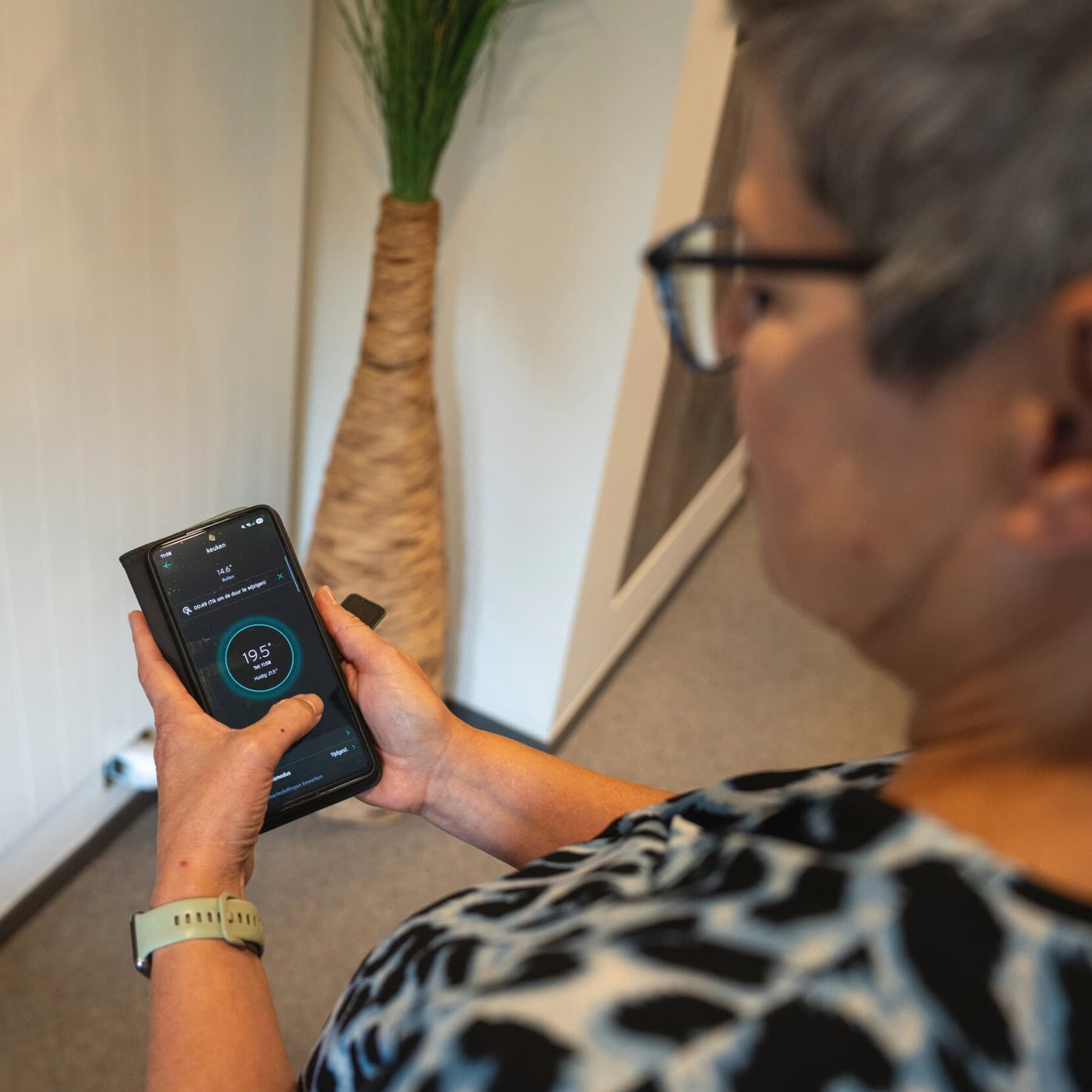 Vrouw toont op haar smartphone hoe ze haar verwarming instelt via een de myvaillant-app