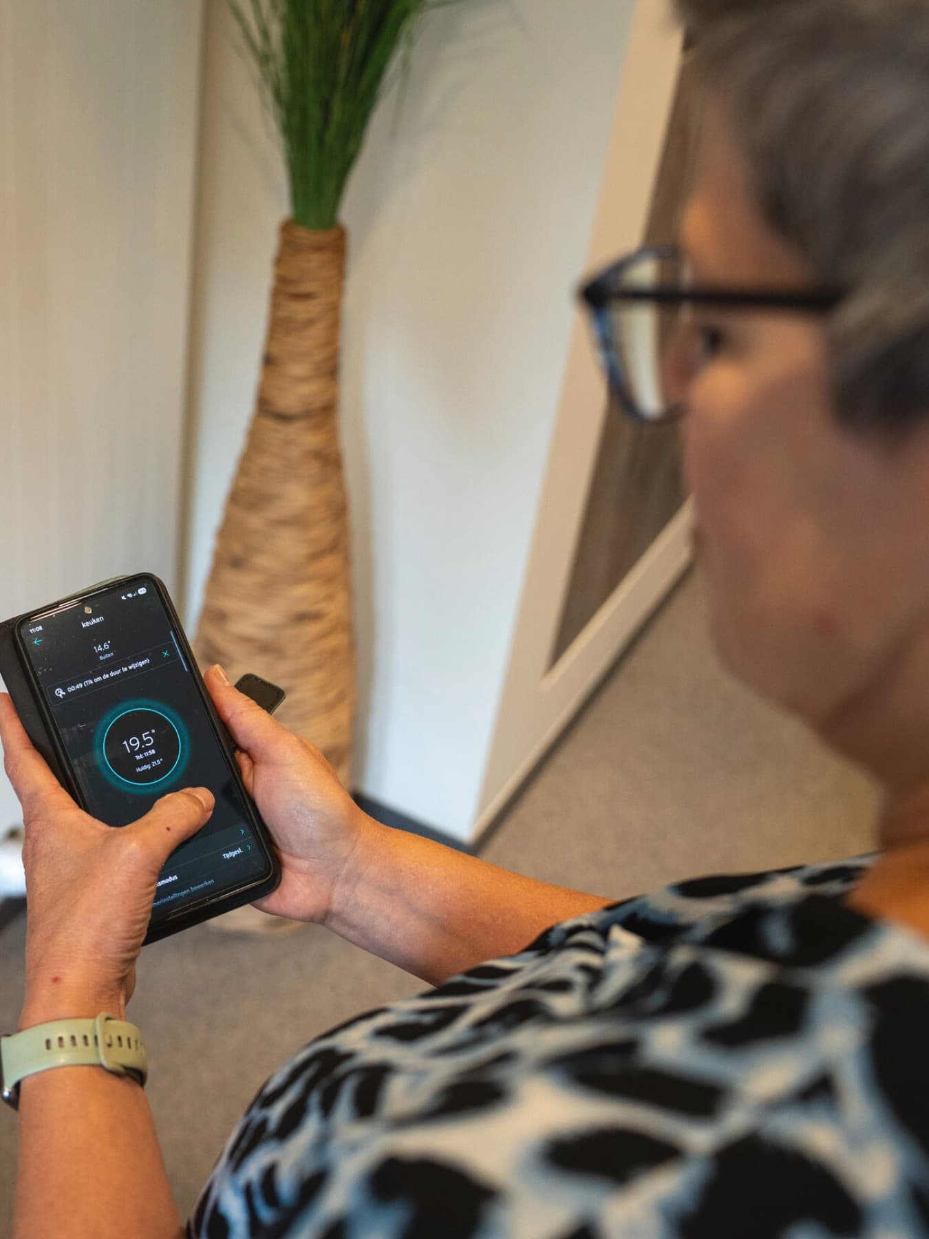 Vrouw toont op haar smartphone hoe ze haar verwarming instelt via een de myvaillant-app