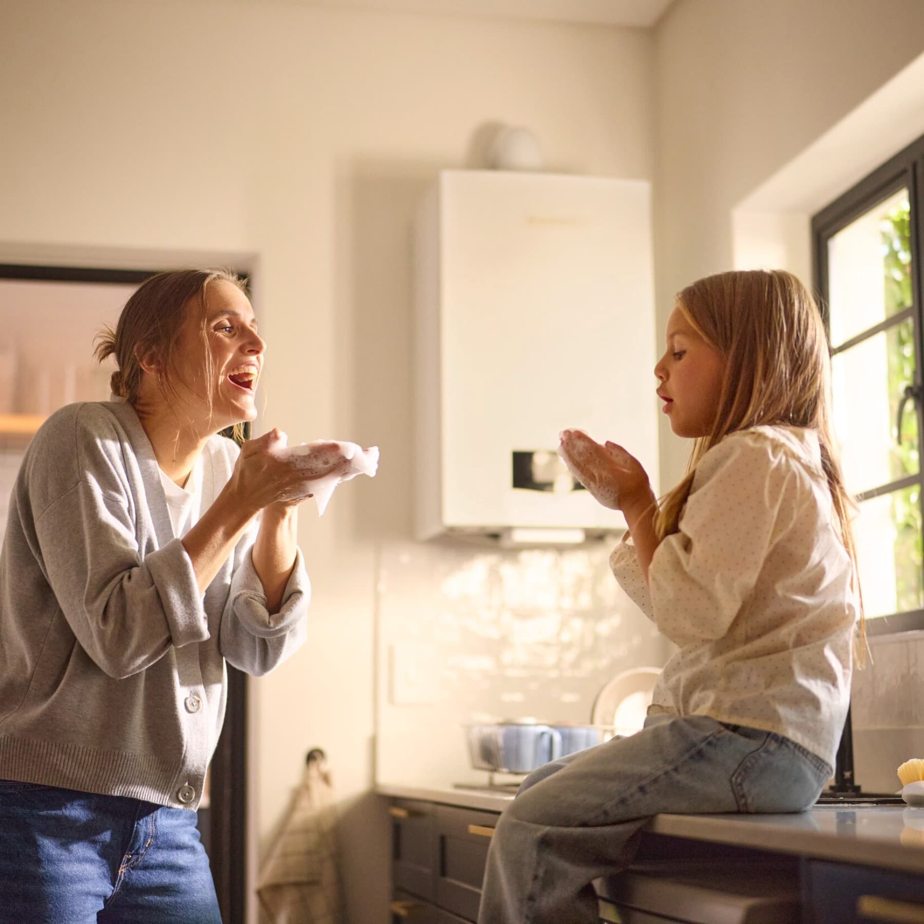 Vrouw en meisje voor een boiler in de keuken